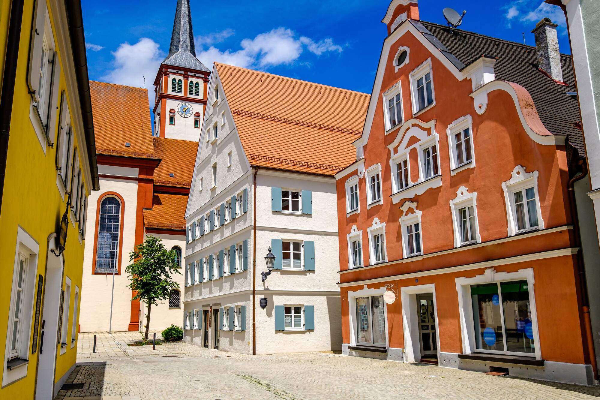 Arquitectura europea: casas coloridas y torre de iglesia en plaza de pueblo.