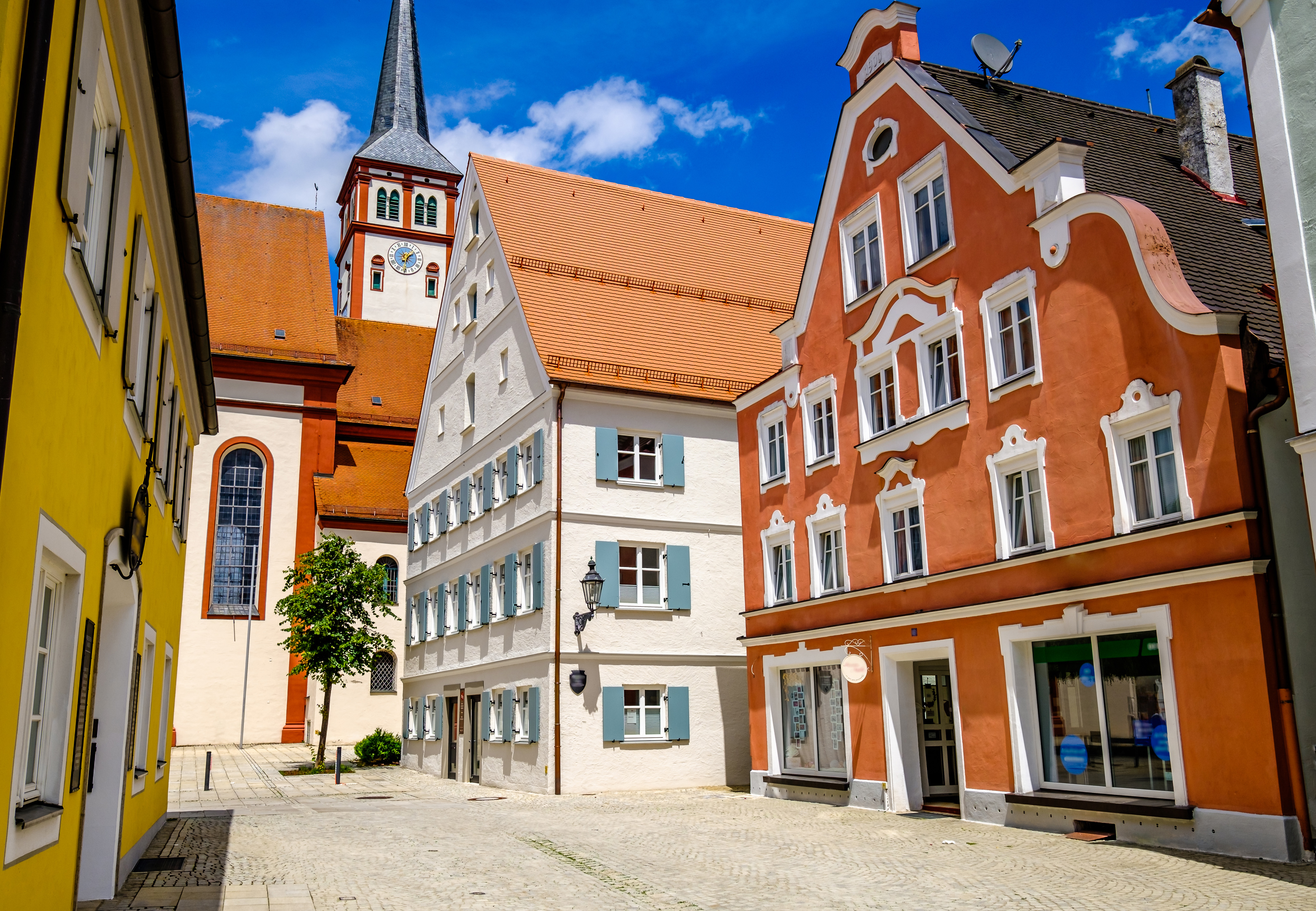 Arquitectura europea: casas coloridas y torre de iglesia en plaza de pueblo.