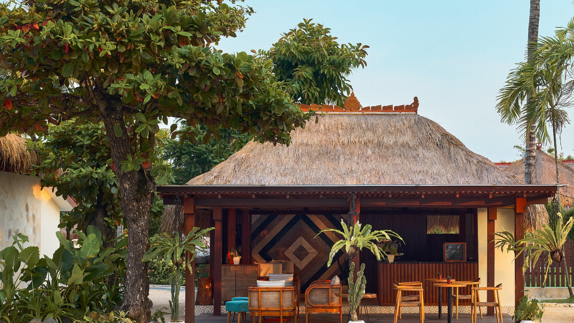 a hut with tables and chairs under a tree