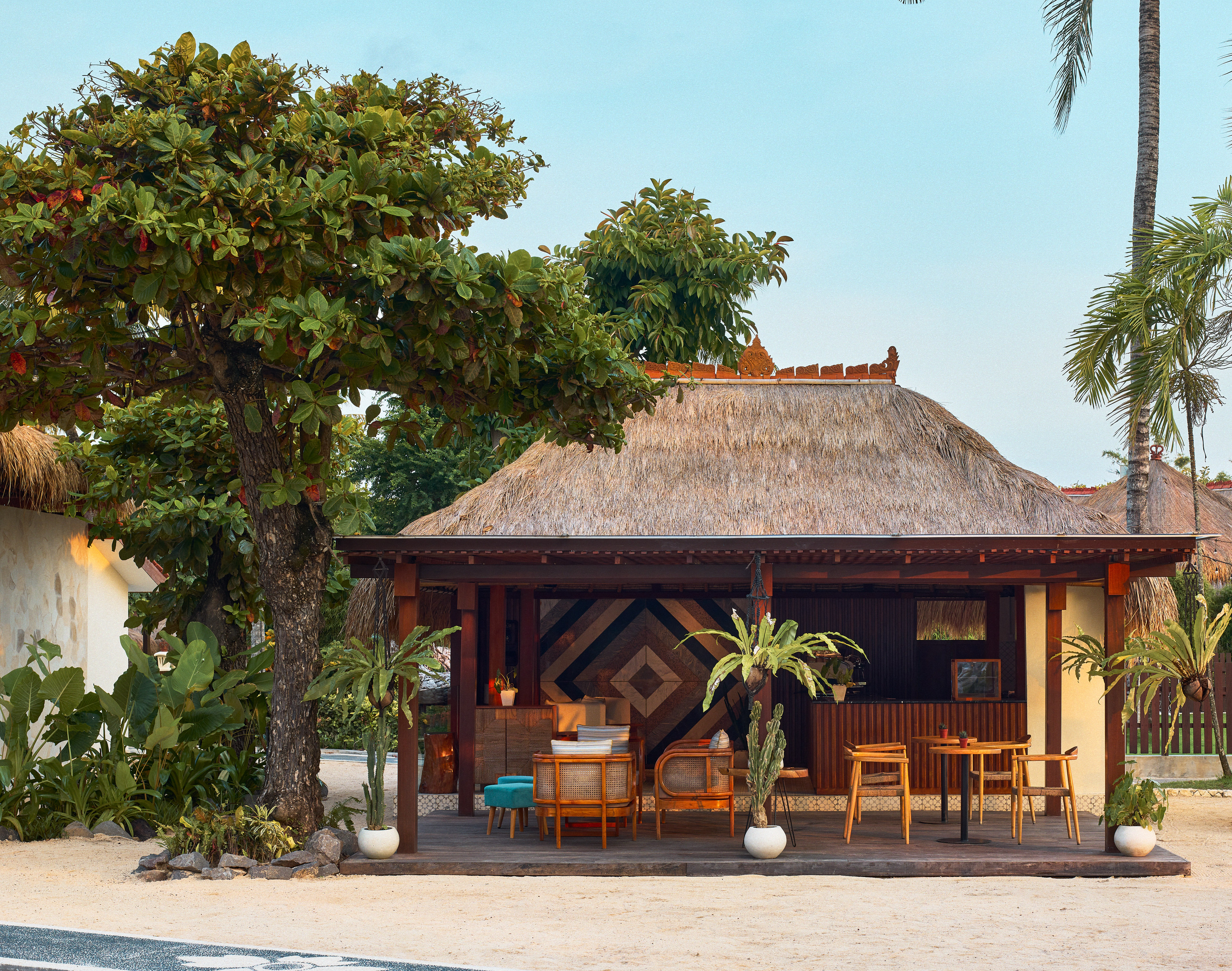 a hut with tables and chairs under a tree