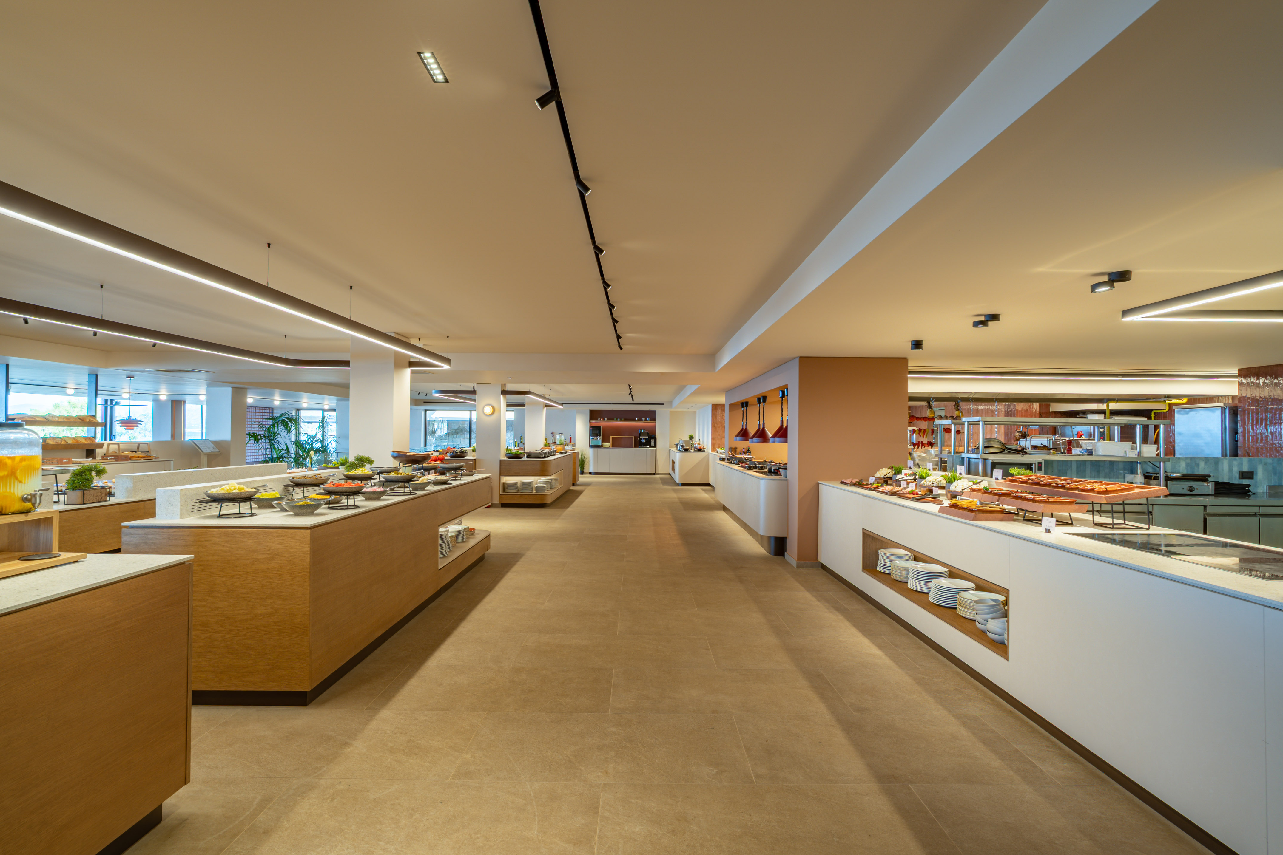 Modern hotel buffet with diverse food stations and bright lighting.