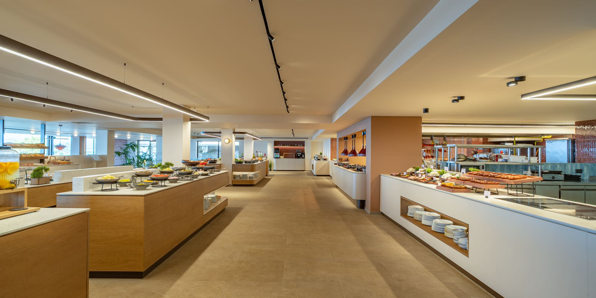 Modern hotel buffet with diverse food stations and bright lighting.