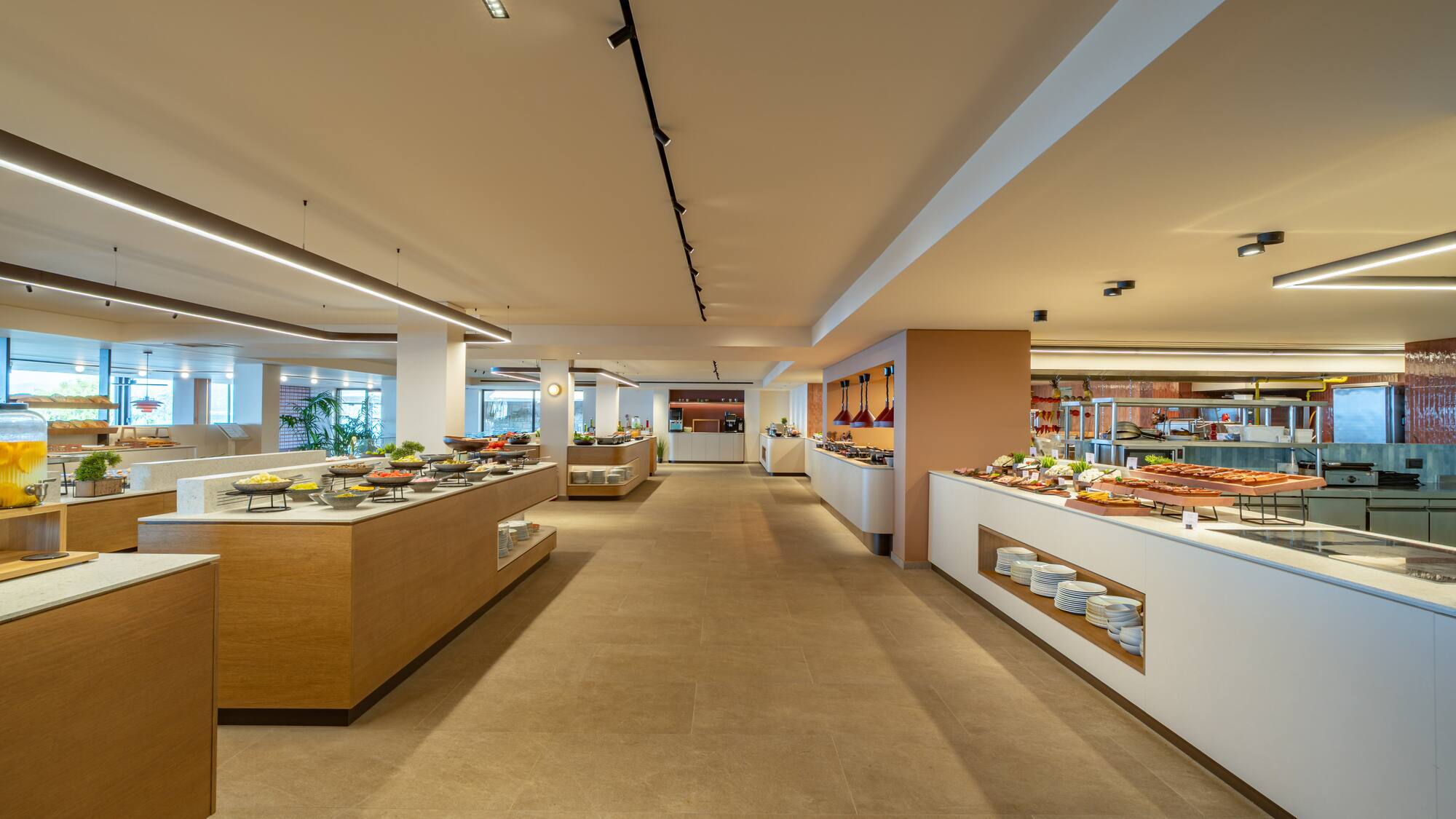 Modern hotel buffet with diverse food stations and bright lighting.