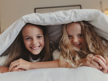 two girls lying under a blanket