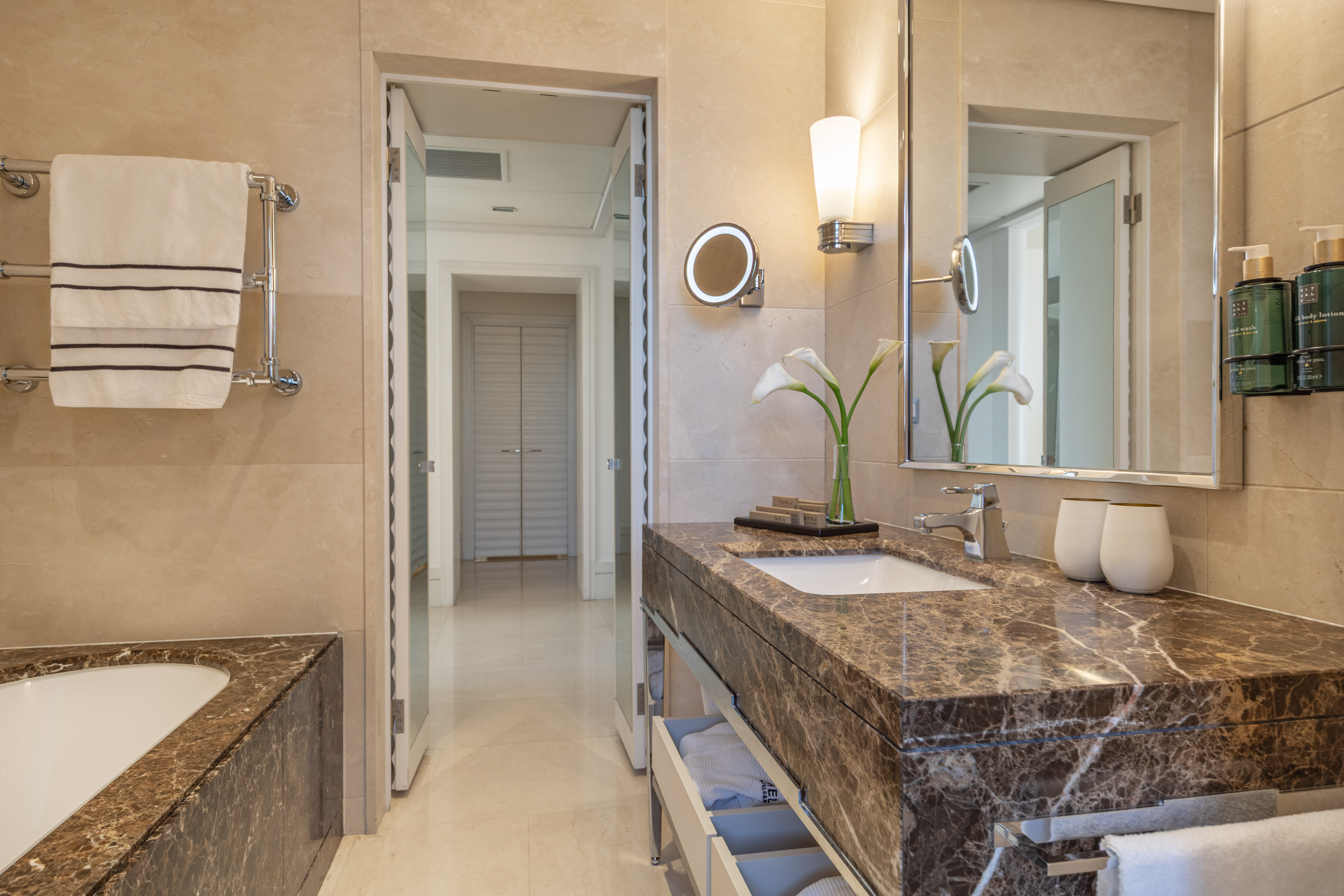 Elegant hotel bathroom featuring marble vanity, modern sink, and bright mirror.