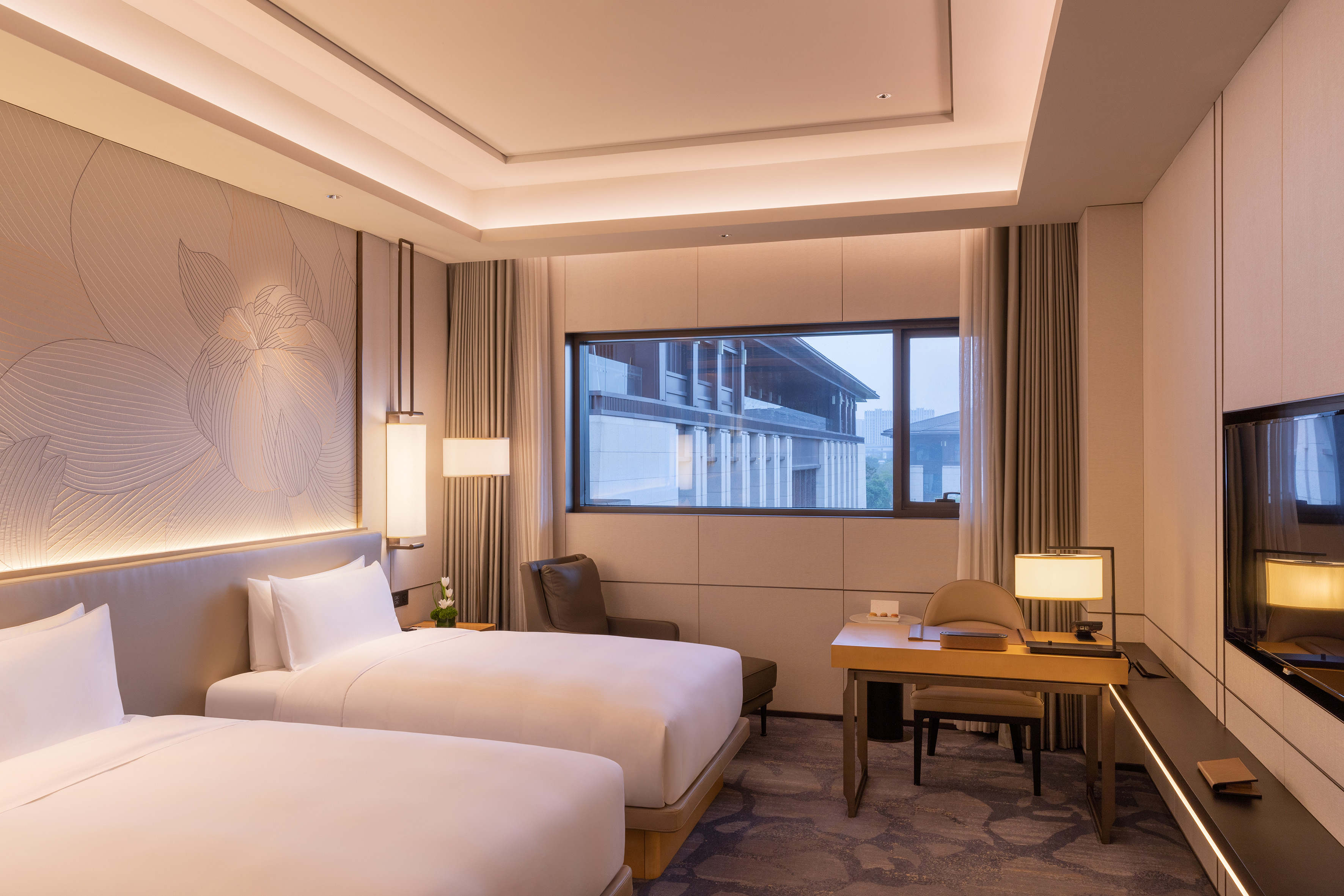 Luxury modern hotel twin room with desk and city view.