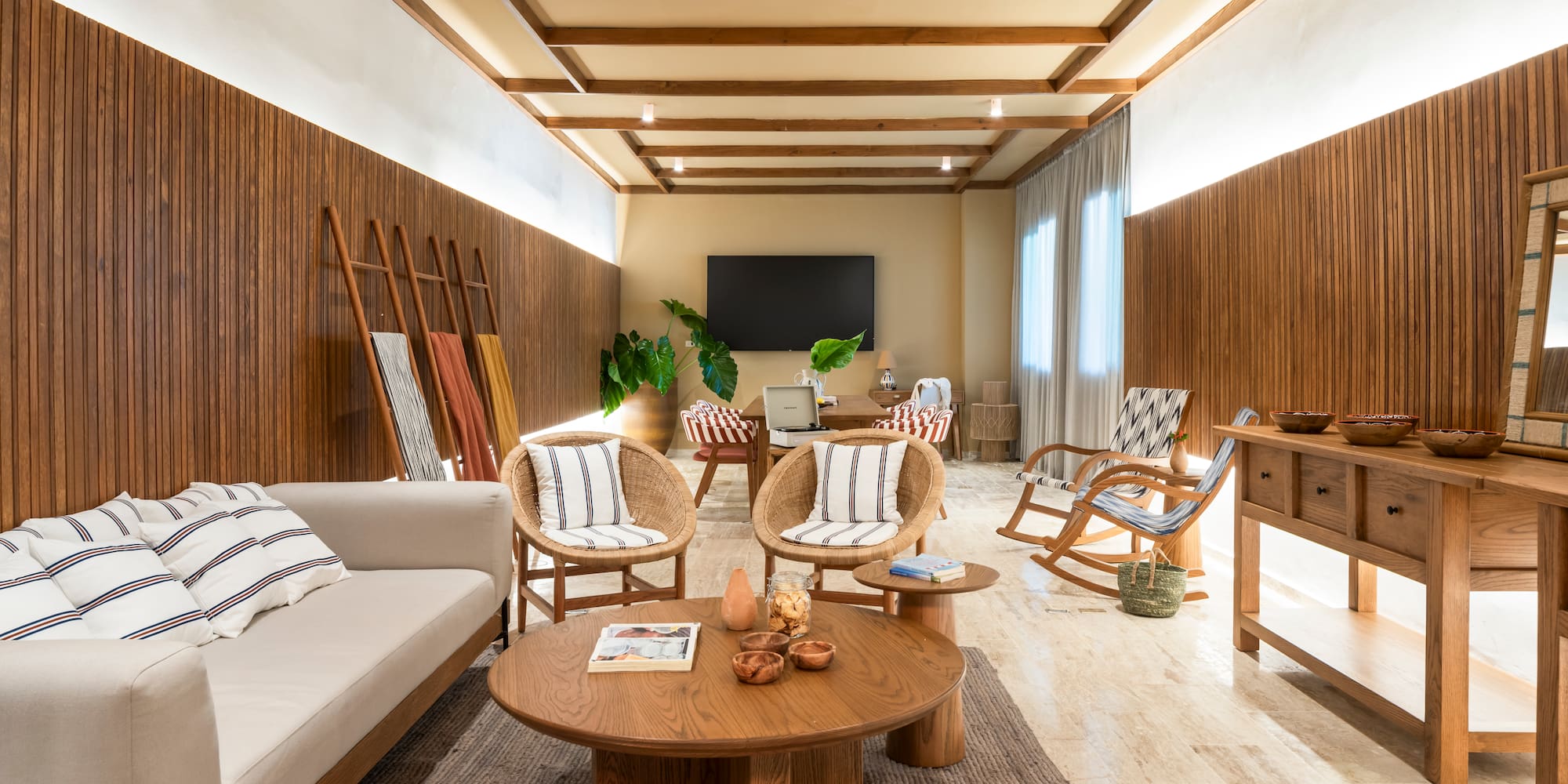 Modern living room with wood paneling, rattan chairs, and neutral decor.