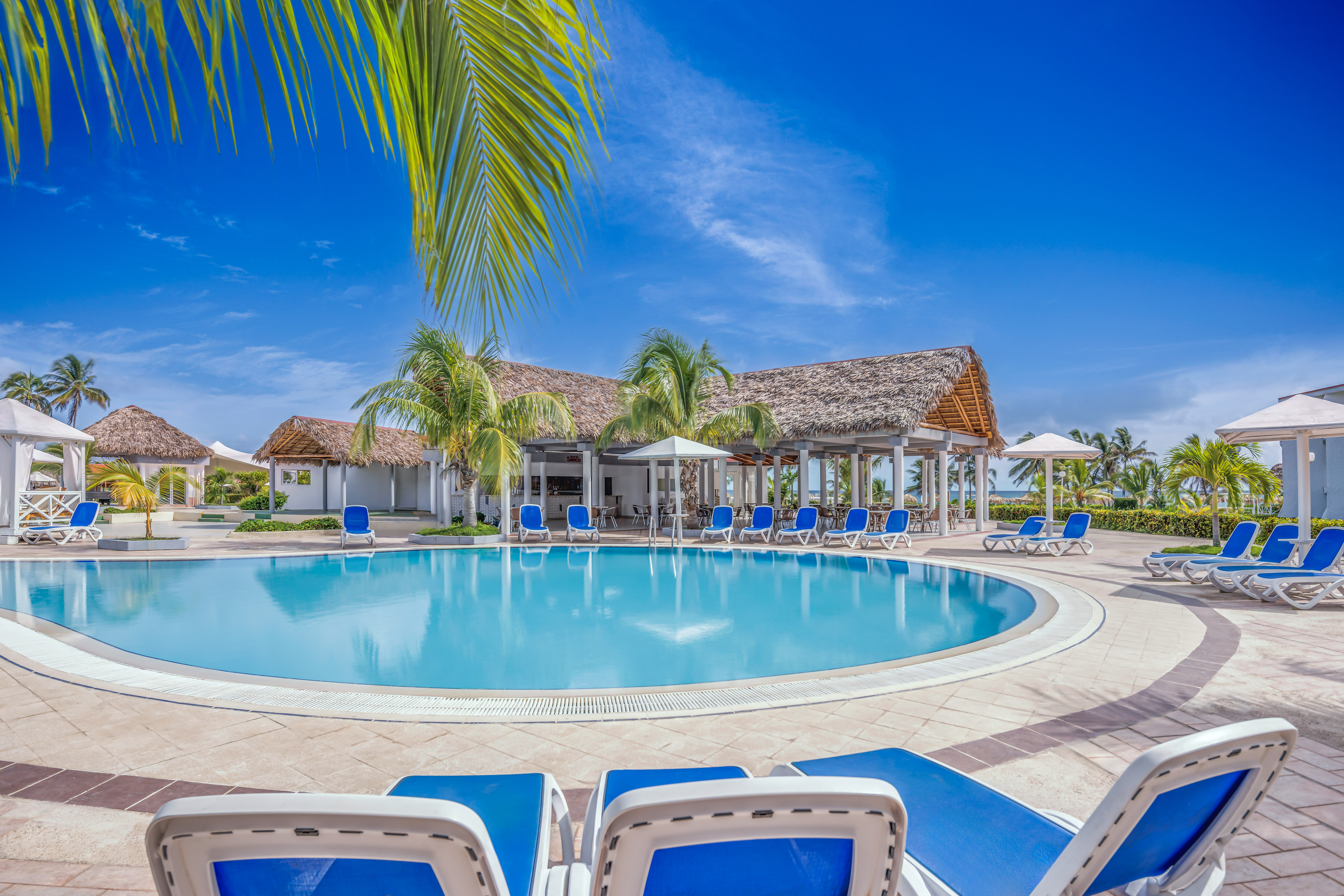 a pool with chairs and umbrellas in front of a building