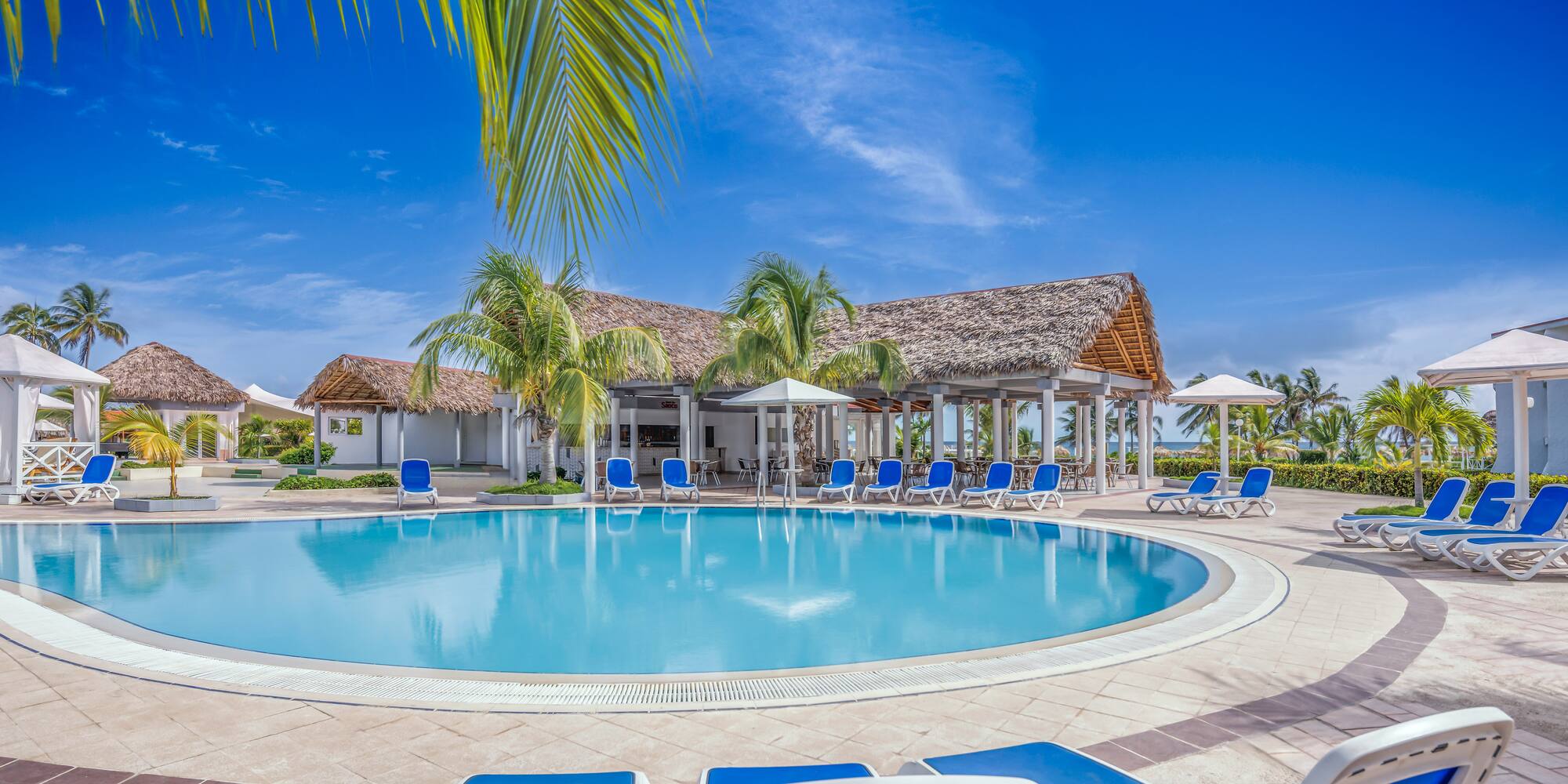 a pool with chairs and umbrellas in front of a building