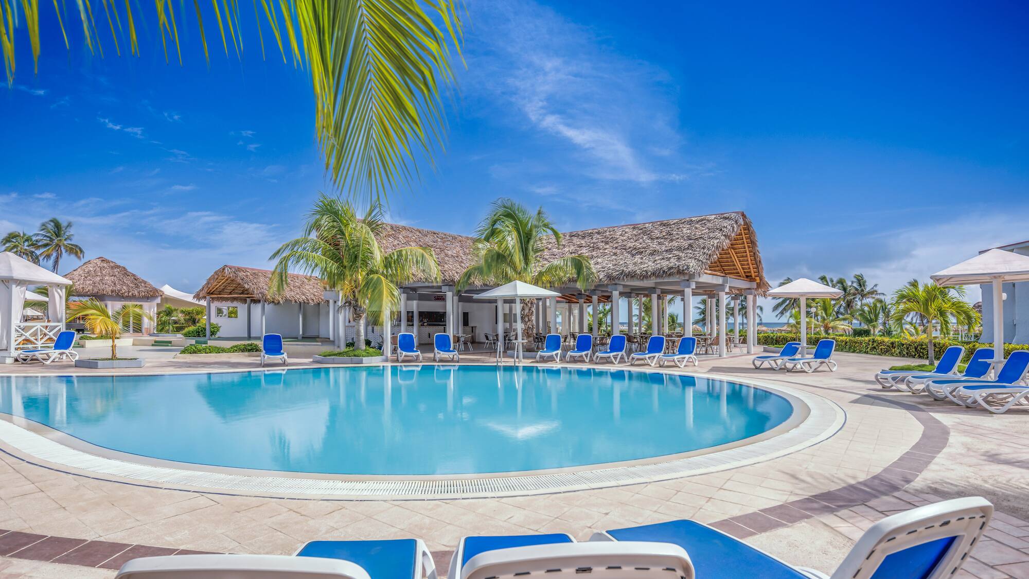 a pool with chairs and umbrellas in front of a building