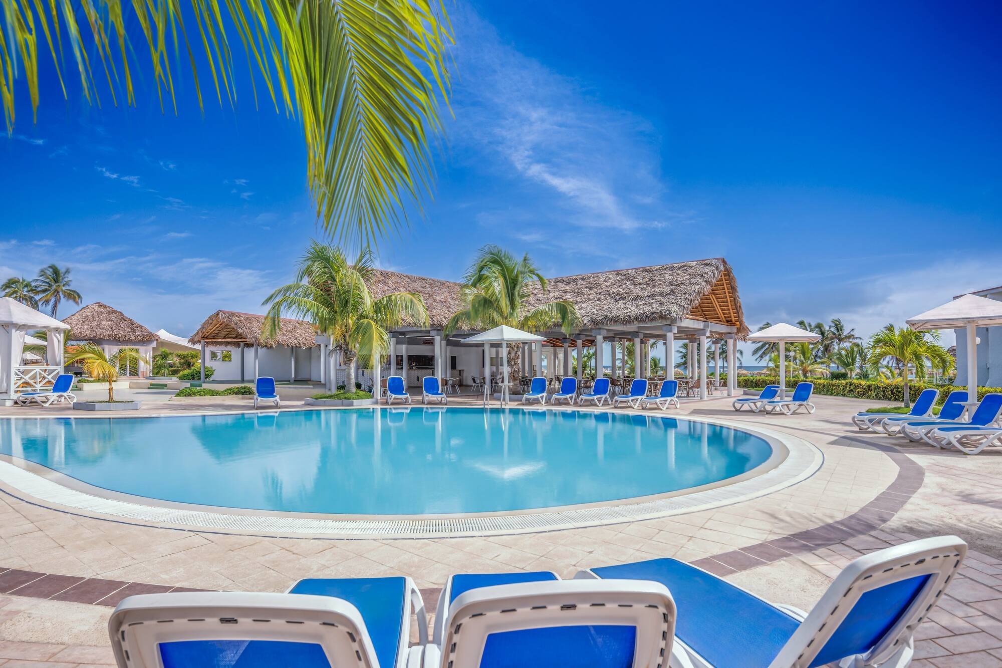 a pool with chairs and umbrellas in front of a building