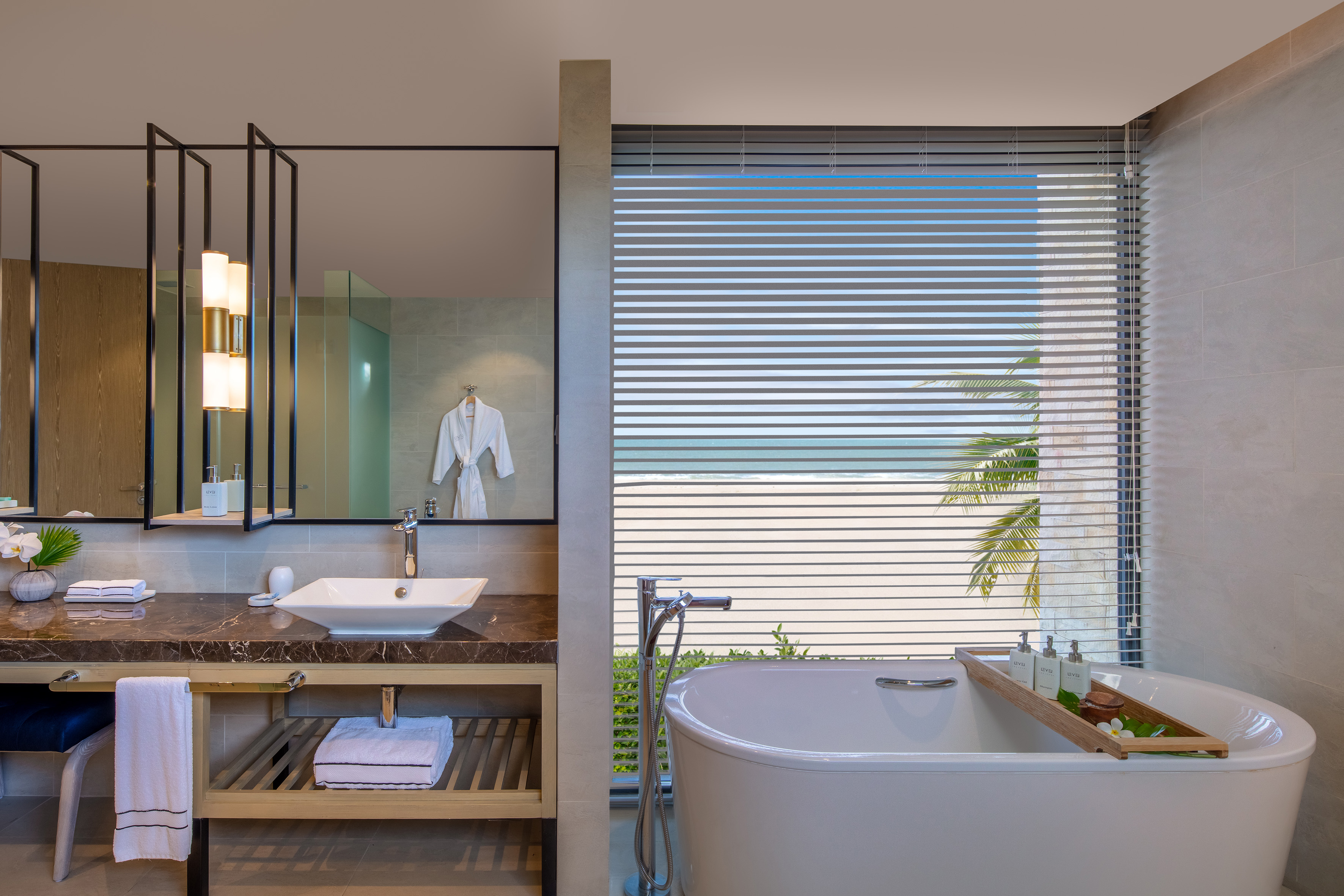Oceanfront luxury bathroom with freestanding tub, modern vanity, and beach view.