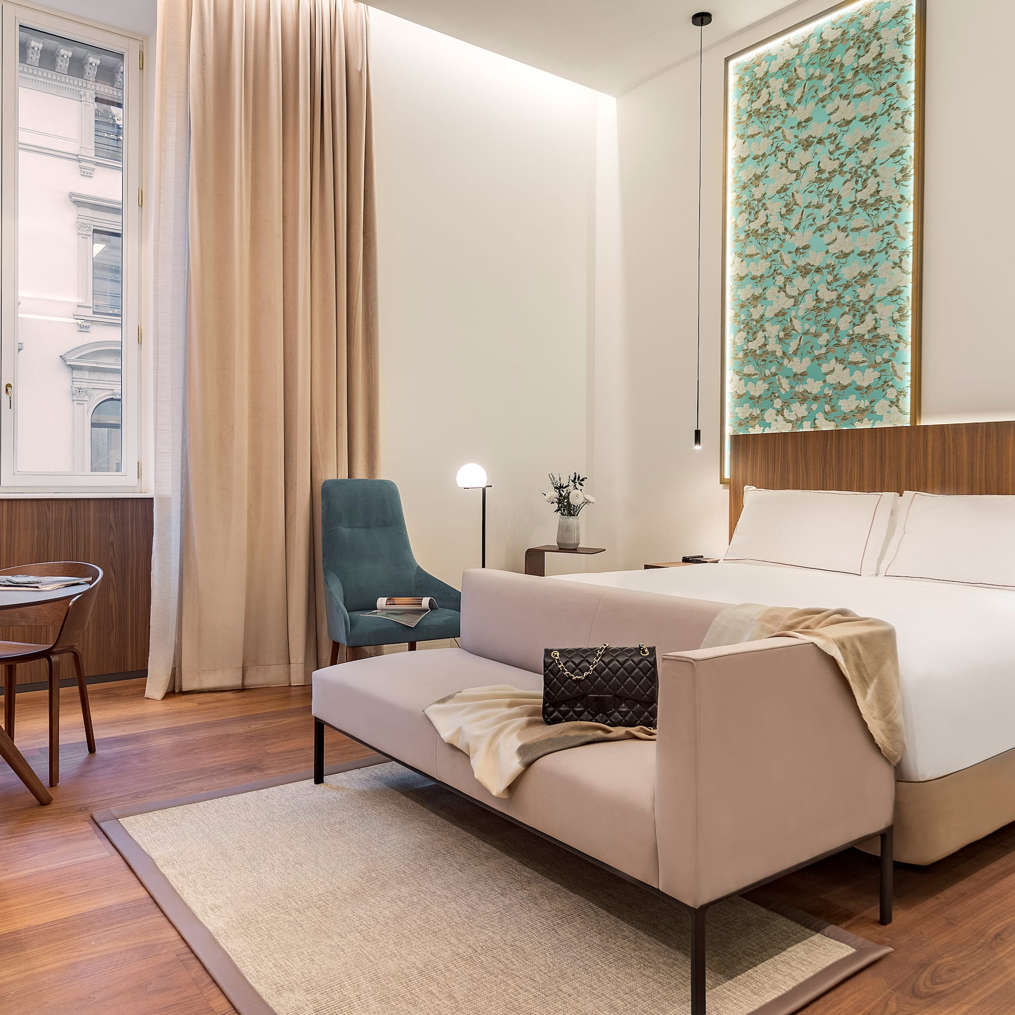 Milan views from a junior suite bedroom with a bed and chair at the Luxury hotel Palazzo Cordusio