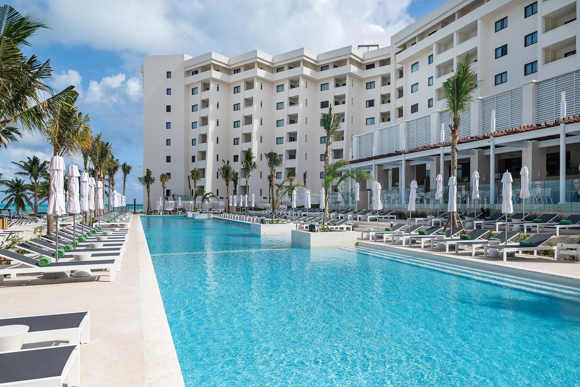 a pool with palm trees and a building in the background