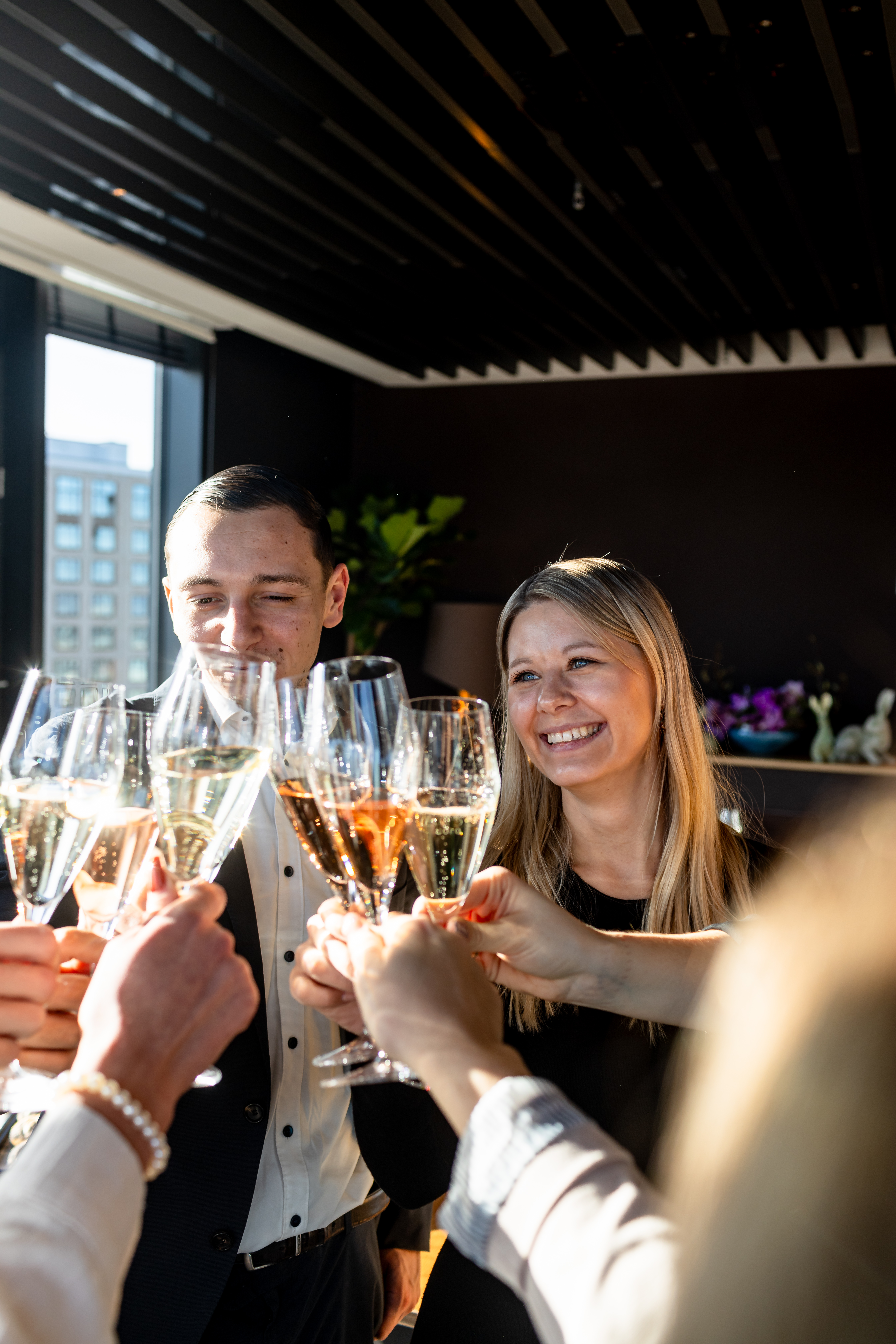 Guests toast champagne glasses at a celebratory event, smiling man and woman.