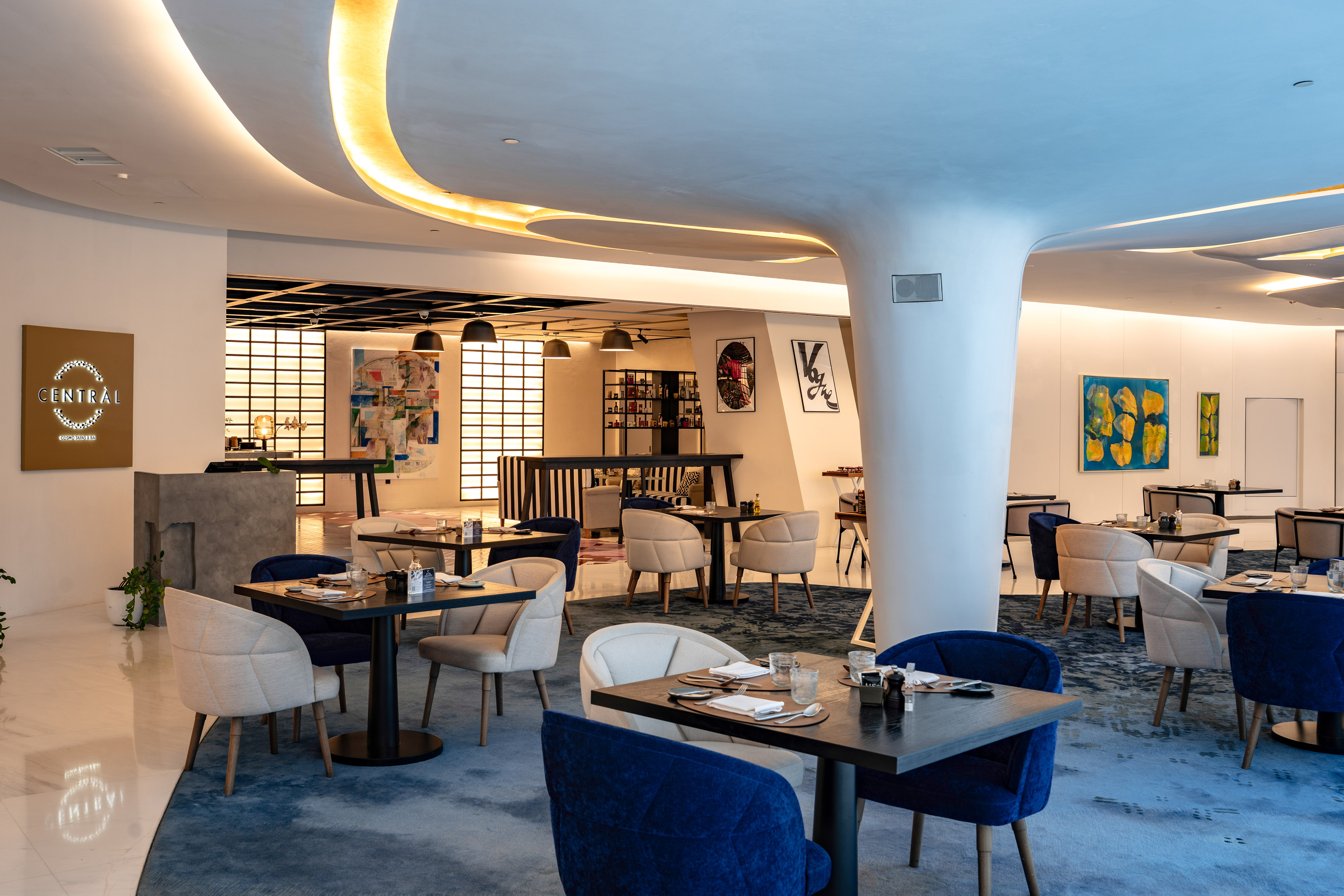 Central restaurant: modern dining, blue carpet, tables, abstract art.