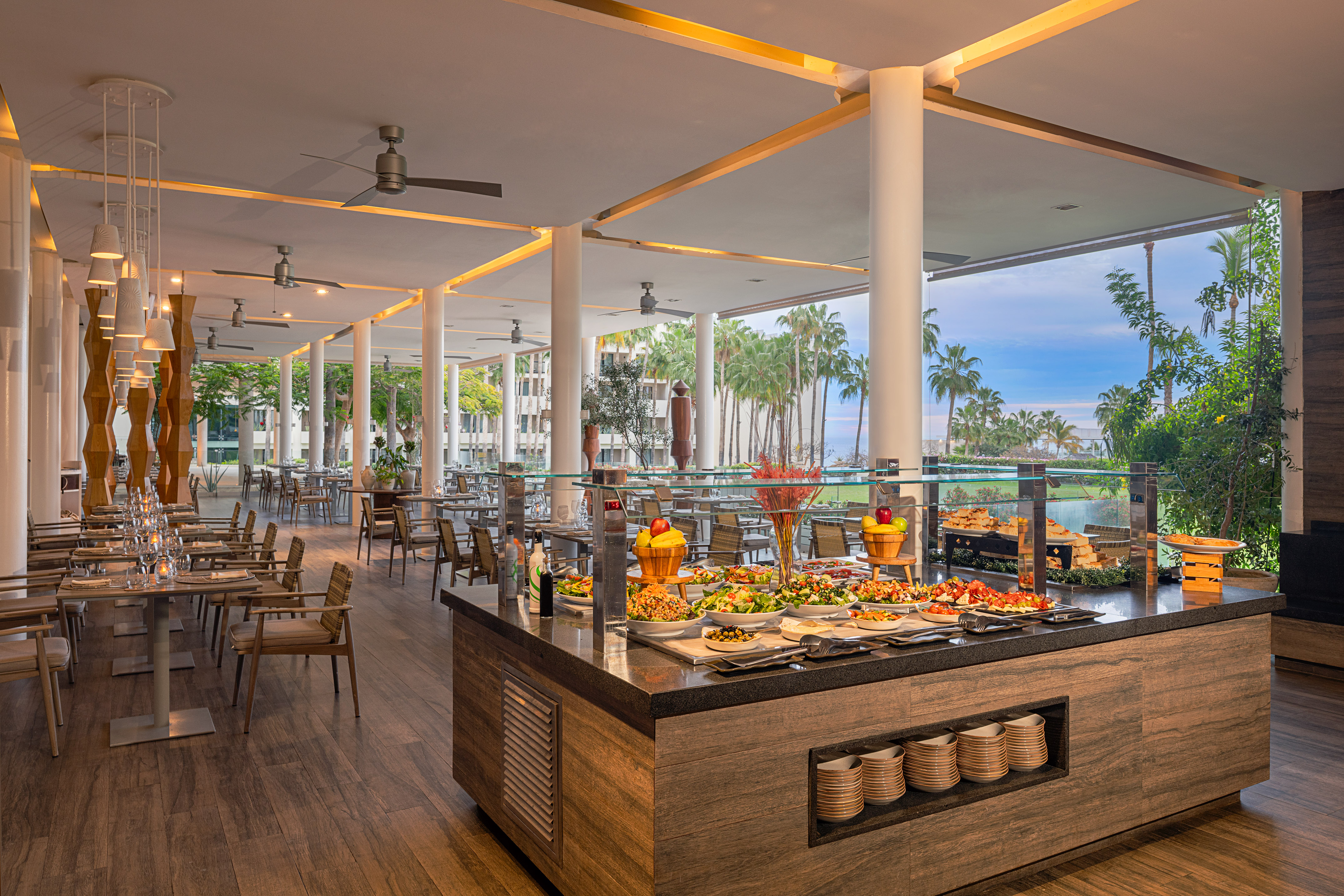 Luxury hotel buffet with fresh food, tropical outdoor dining, palm trees, ocean view.