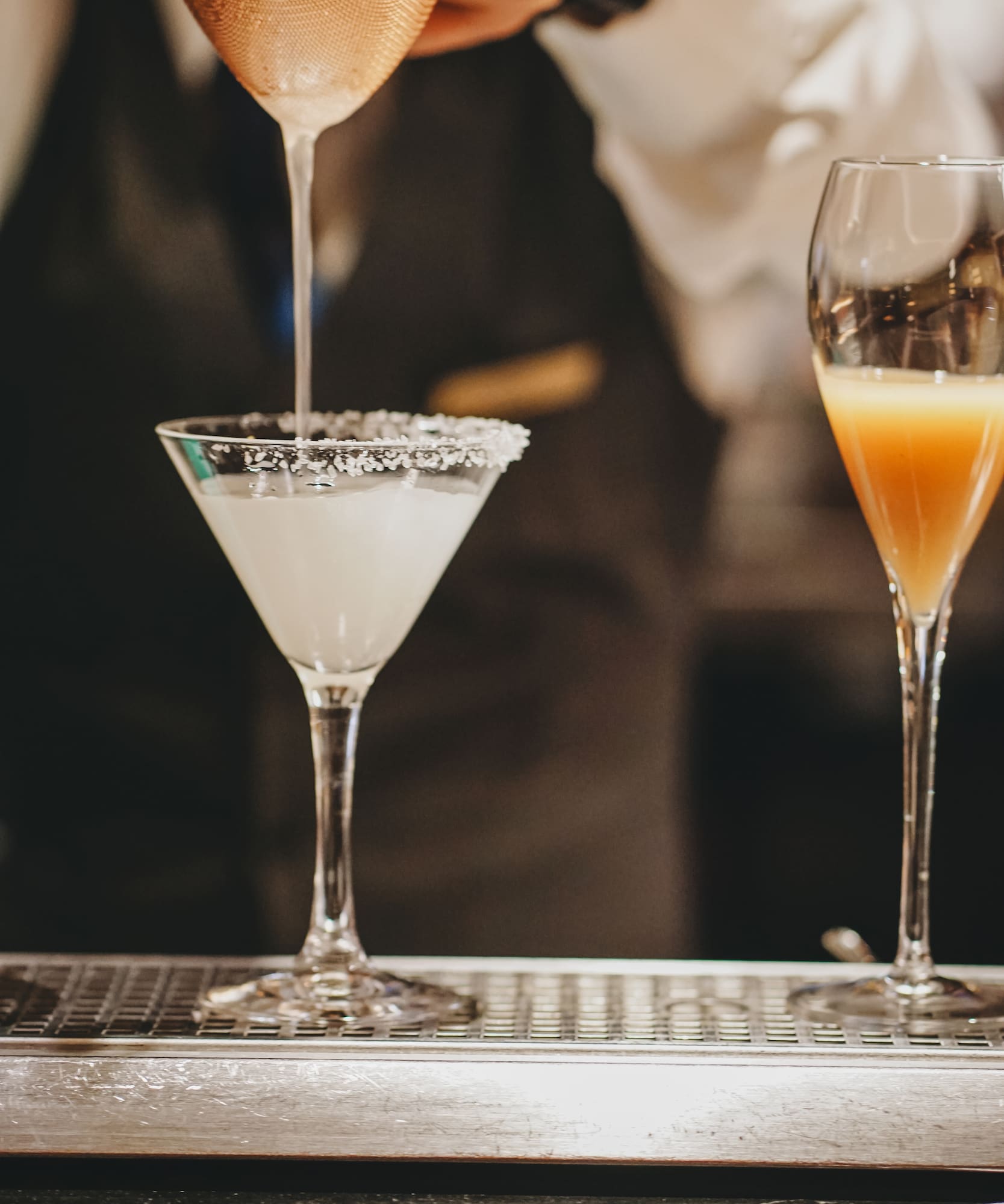 a person pouring liquid into a martini glass