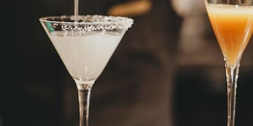 a person pouring liquid into a martini glass