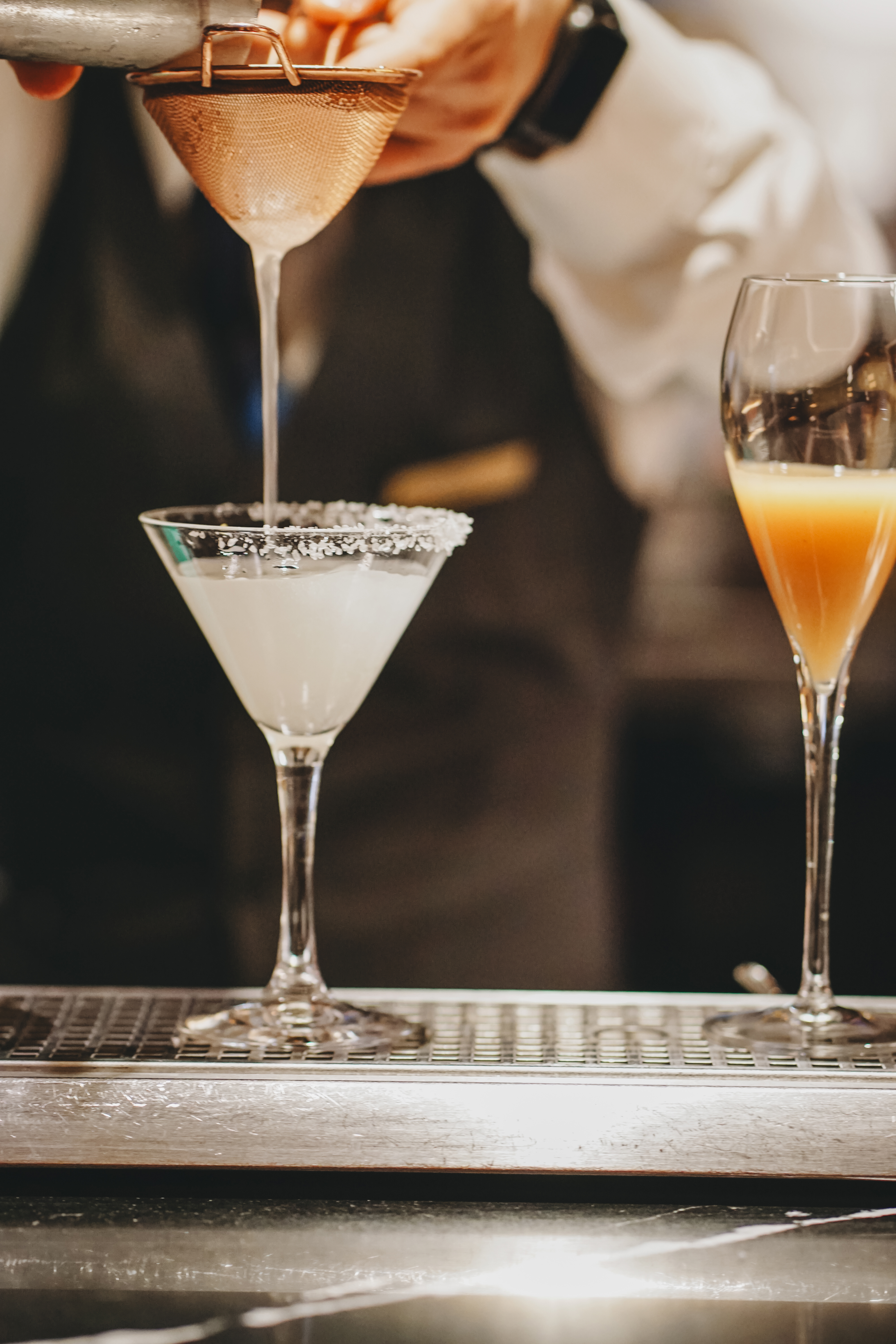 a person pouring liquid into a martini glass