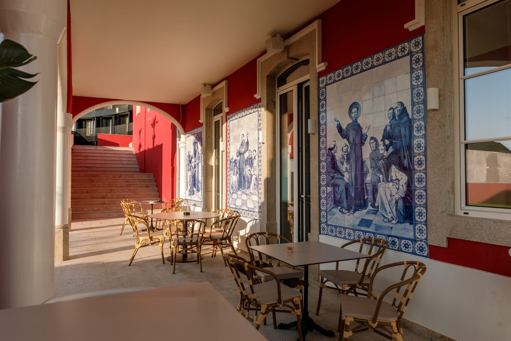 Cafe terrace with red walls, rattan seating, and blue azulejo tiles.
