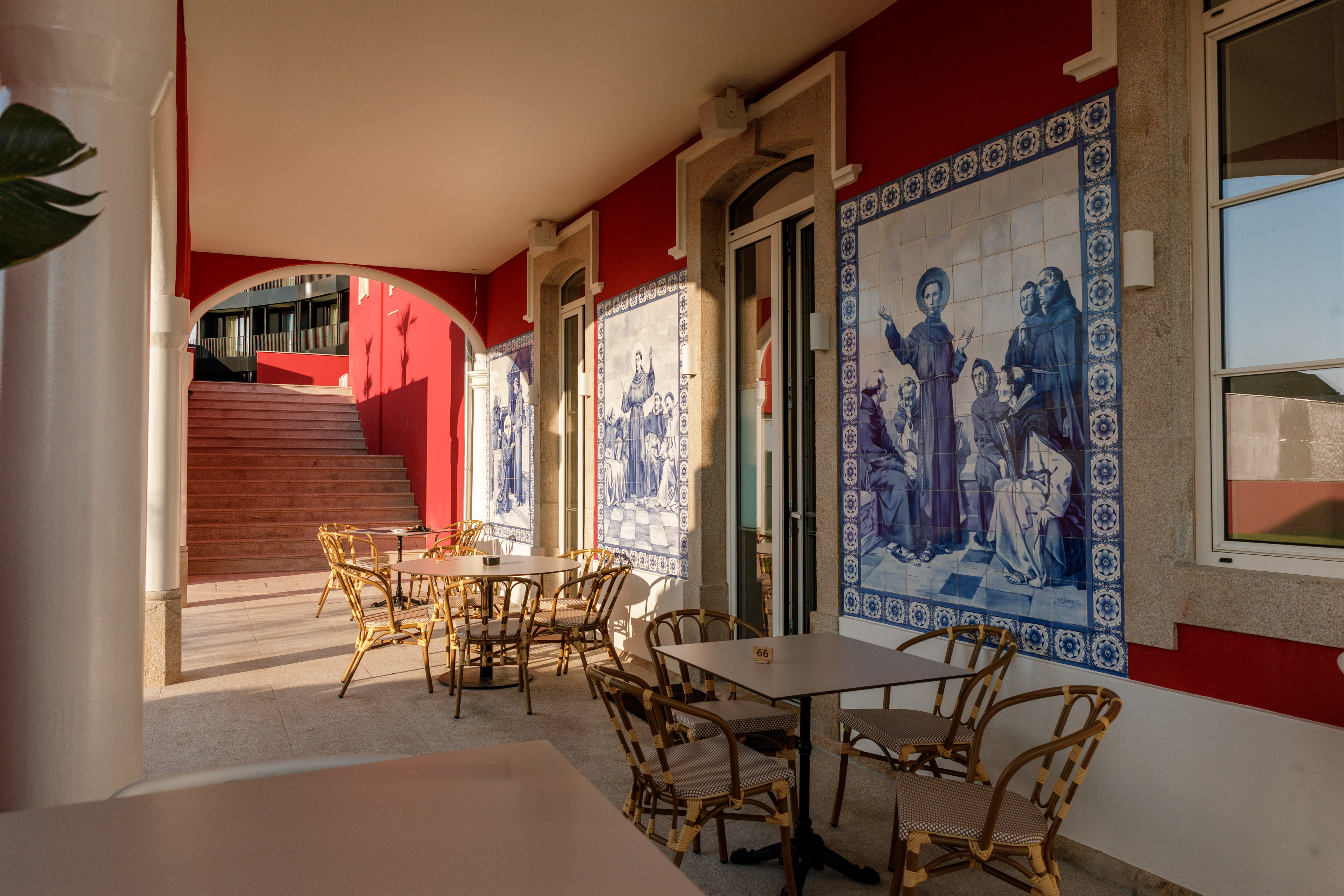 Cafe terrace with red walls, rattan seating, and blue azulejo tiles.