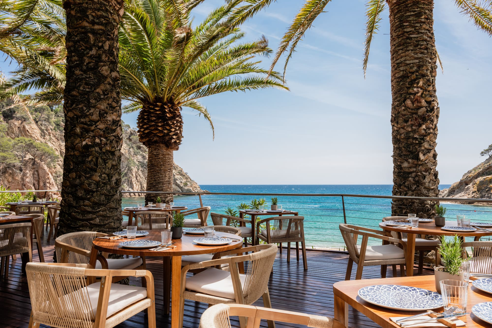 Tropical outdoor restaurant on a wooden deck with sea views and palm trees.