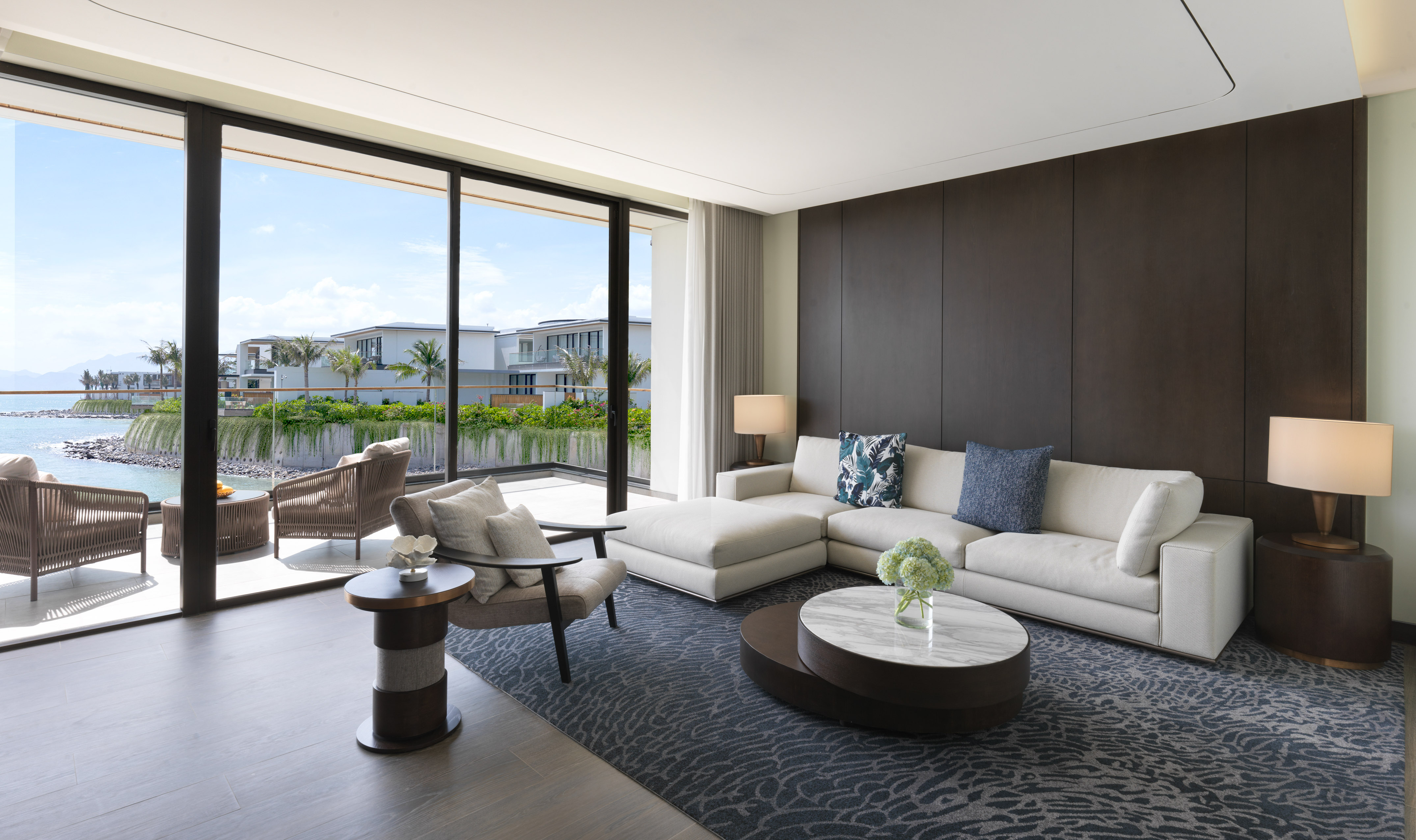 Modern luxury living room with ocean view, white sofa, and balcony.