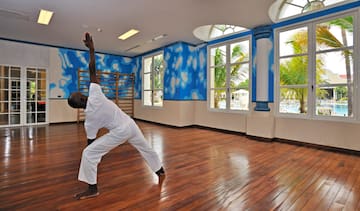 a man in a white uniform doing yoga in a room with blue walls and windows