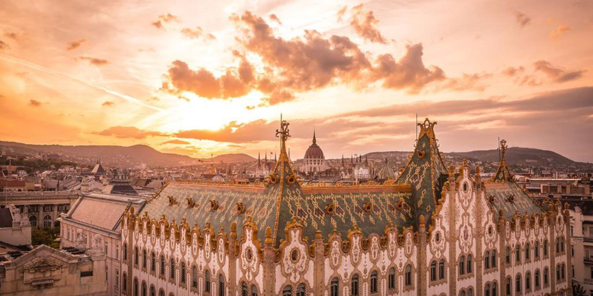 a large building with gold trim and a city in the background