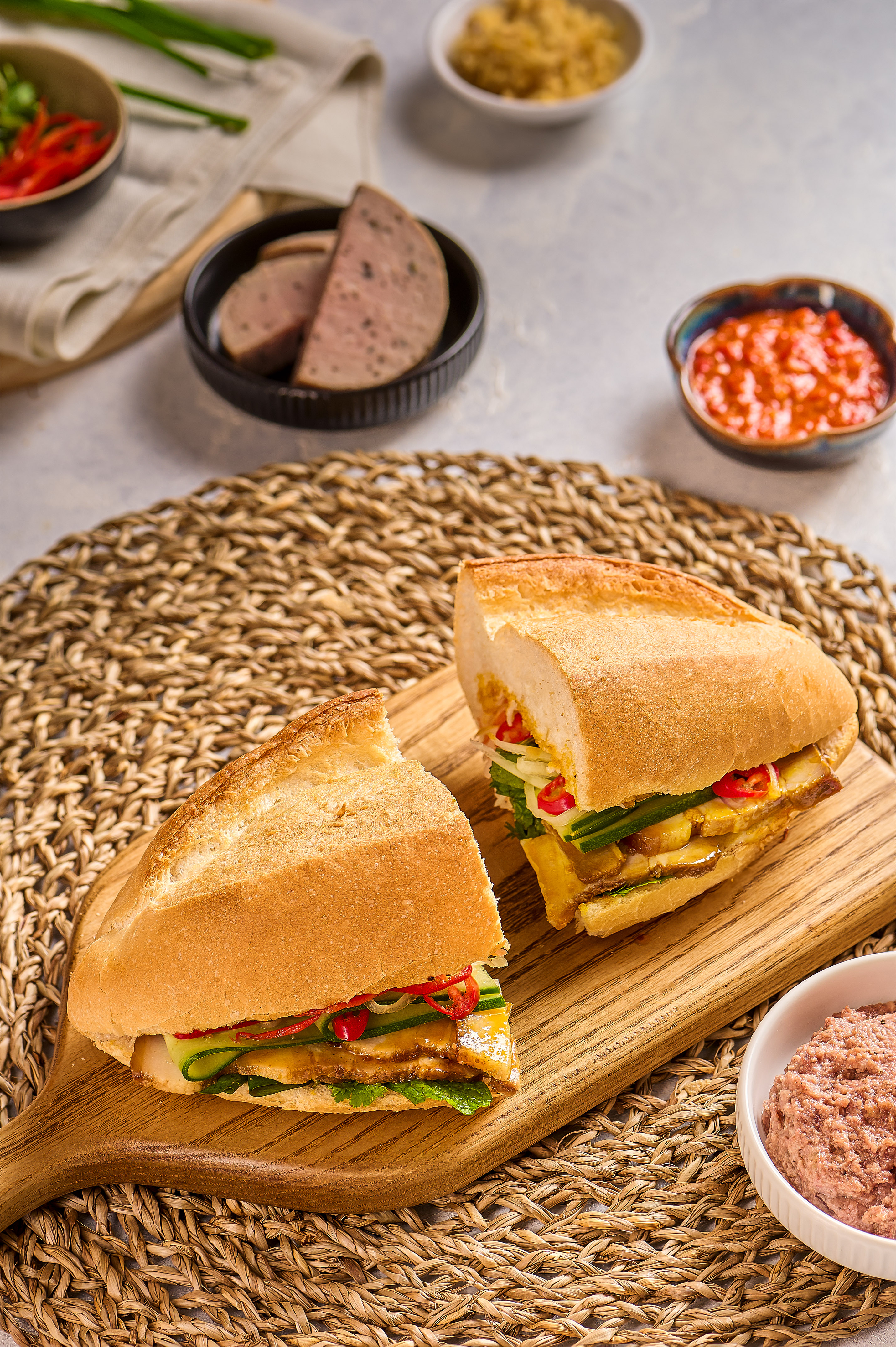 Fresh Banh Mi sandwich with pork, cucumber, chili, and pate on a wooden board.