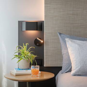 a table with a plant on it next to a bed