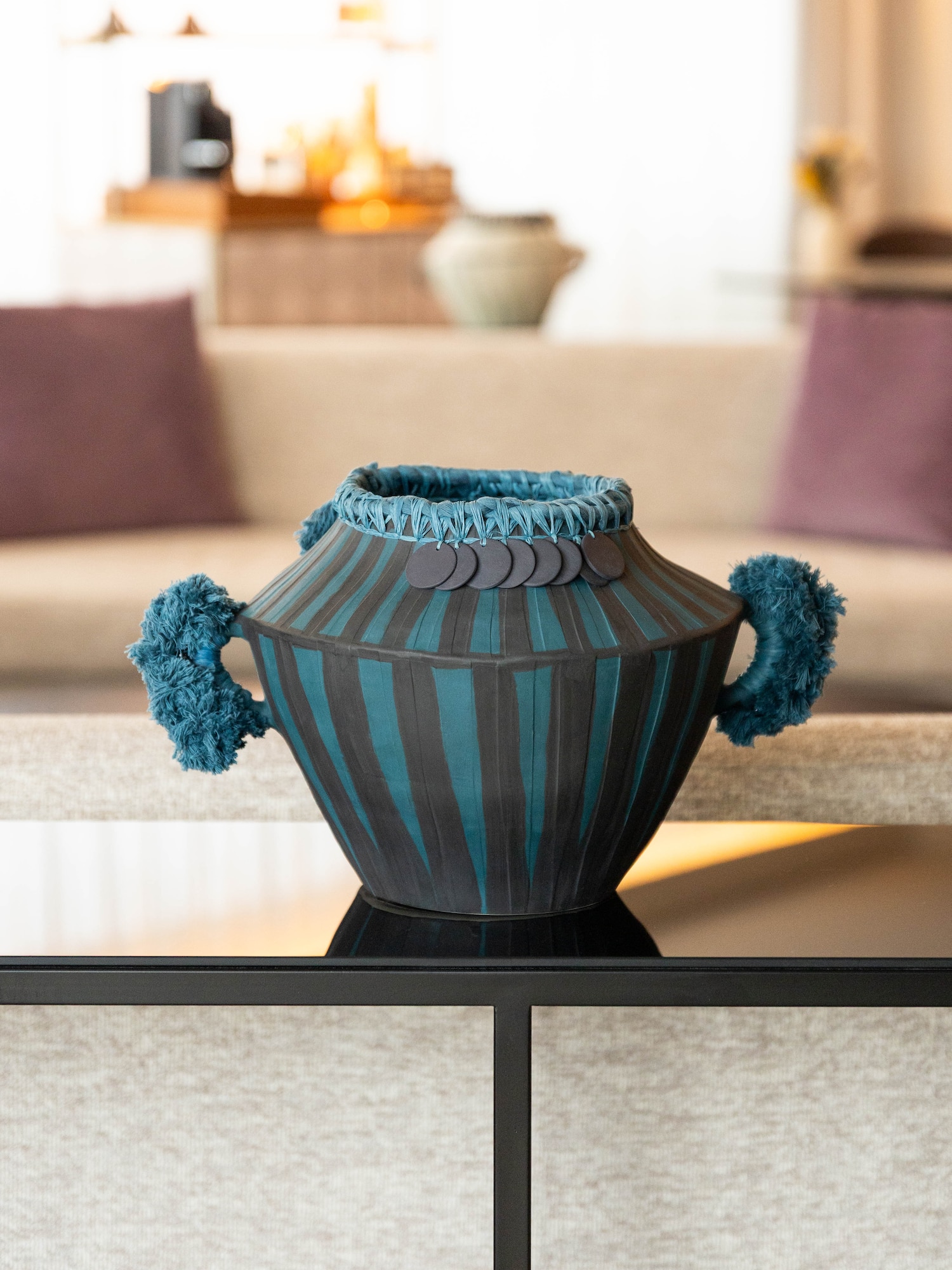 Teal and black striped decorative vase with braided rim, fuzzy handles.