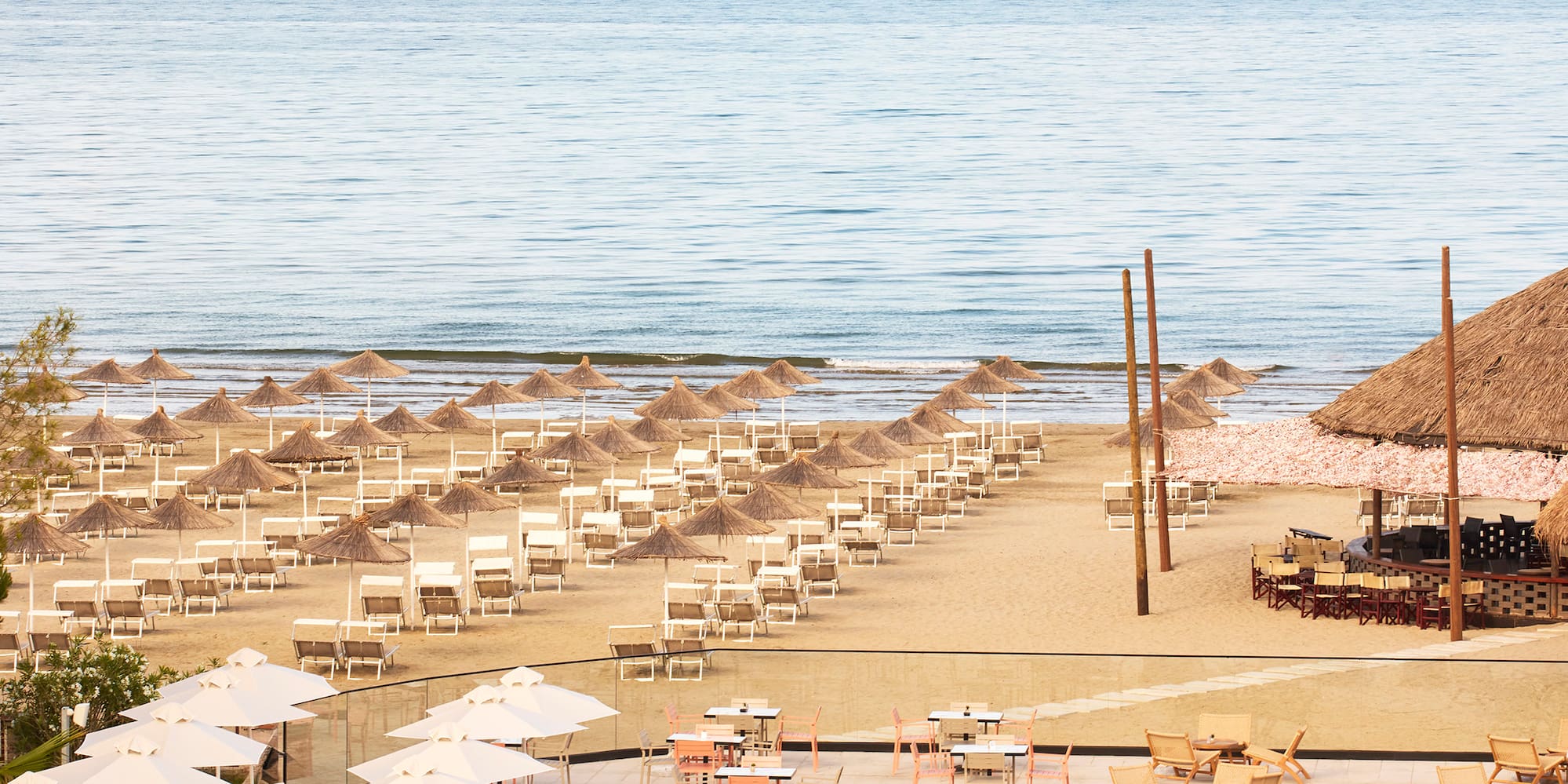 a pool with umbrellas and chairs on a beach