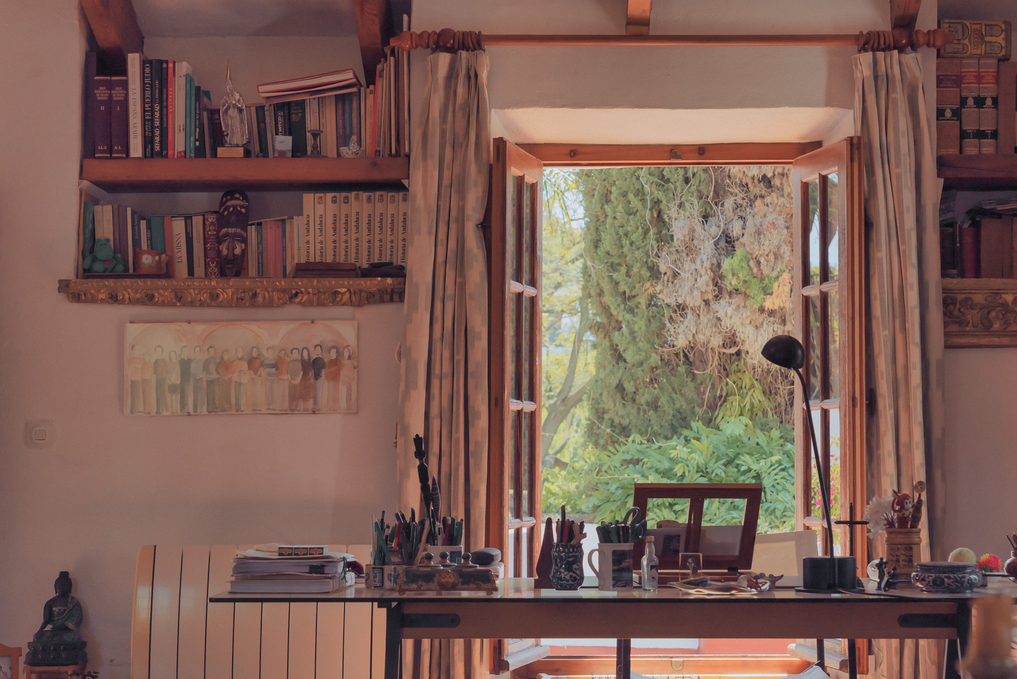 a room with a window open to a table and bookshelf