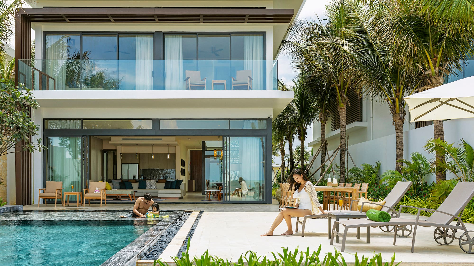 Modern luxury villa with private pool, tropical garden, and people relaxing.