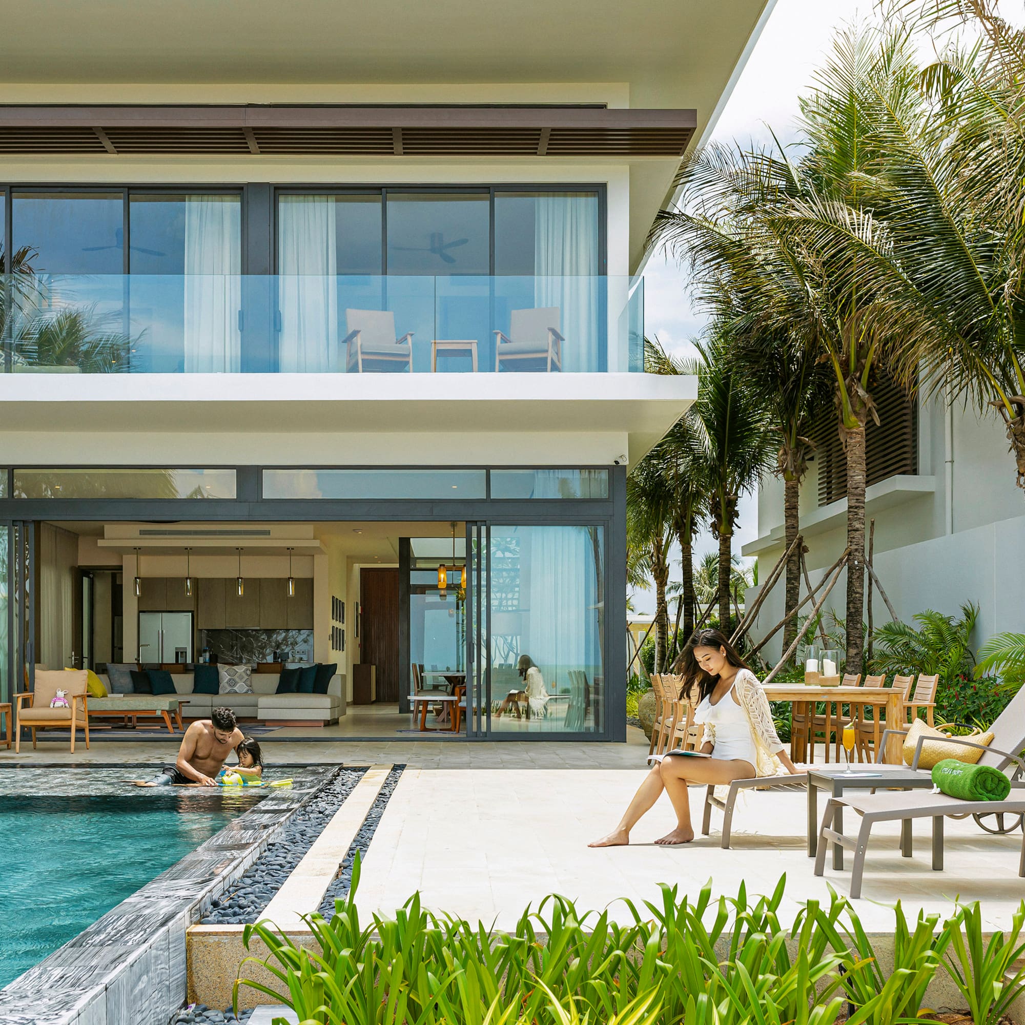 Modern luxury villa with private pool, tropical garden, and people relaxing.