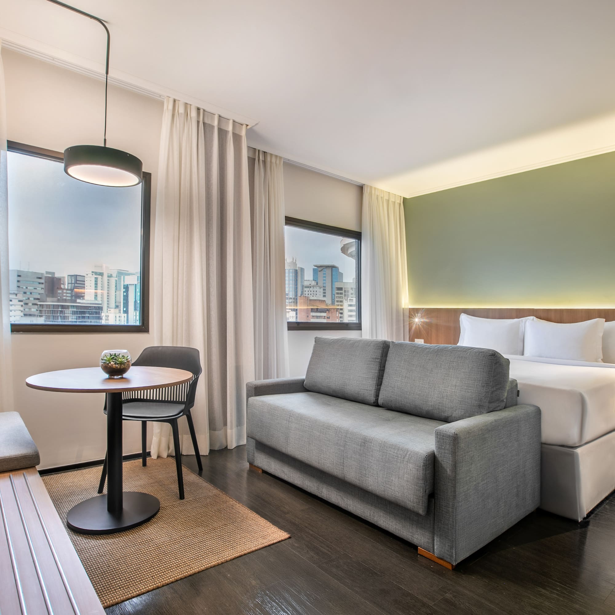 Habitación hotel moderna: sofá cama, cama doble, mesa y vistas a la ciudad.
