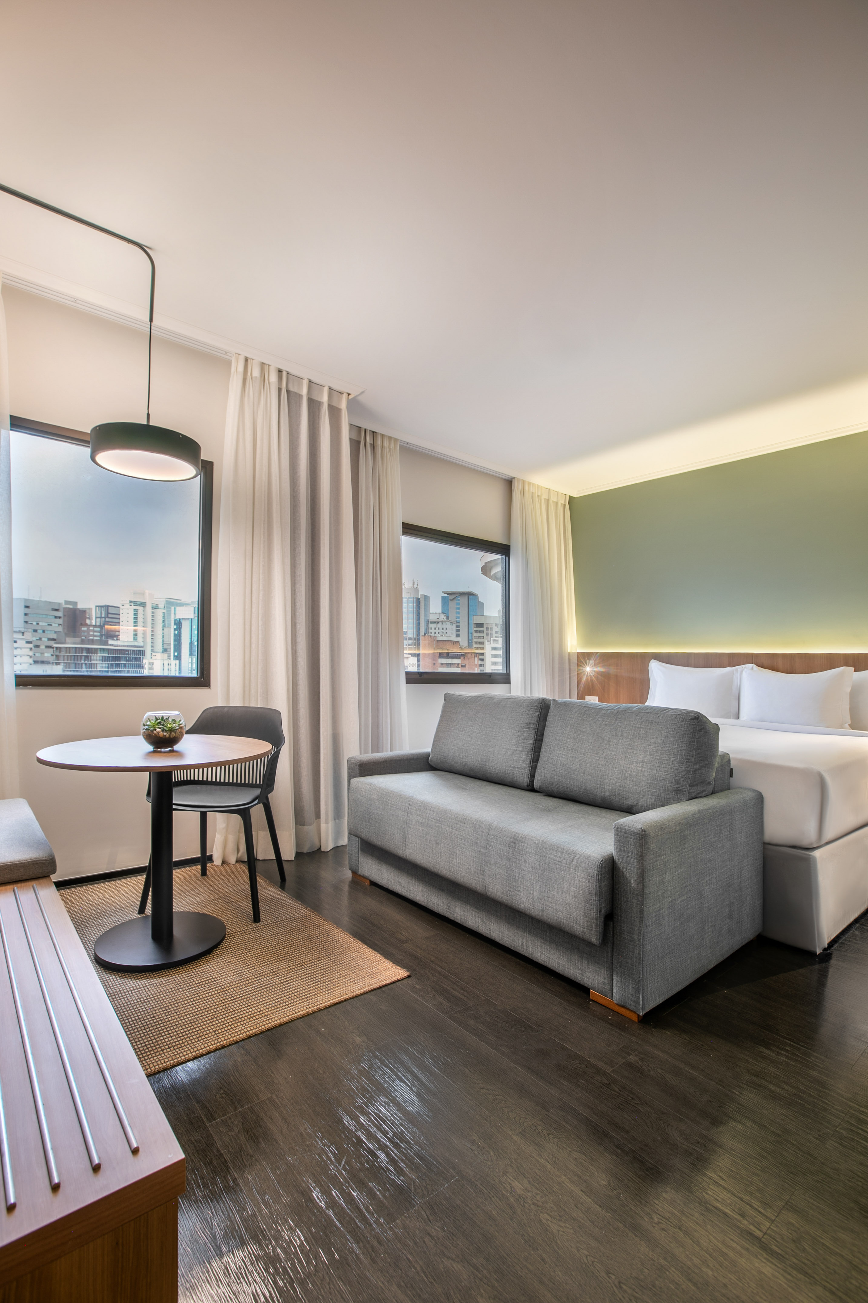 Habitación hotel moderna: sofá cama, cama doble, mesa y vistas a la ciudad.