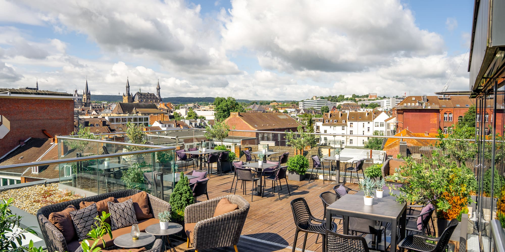 a rooftop patio with chairs and tables and a city in the background