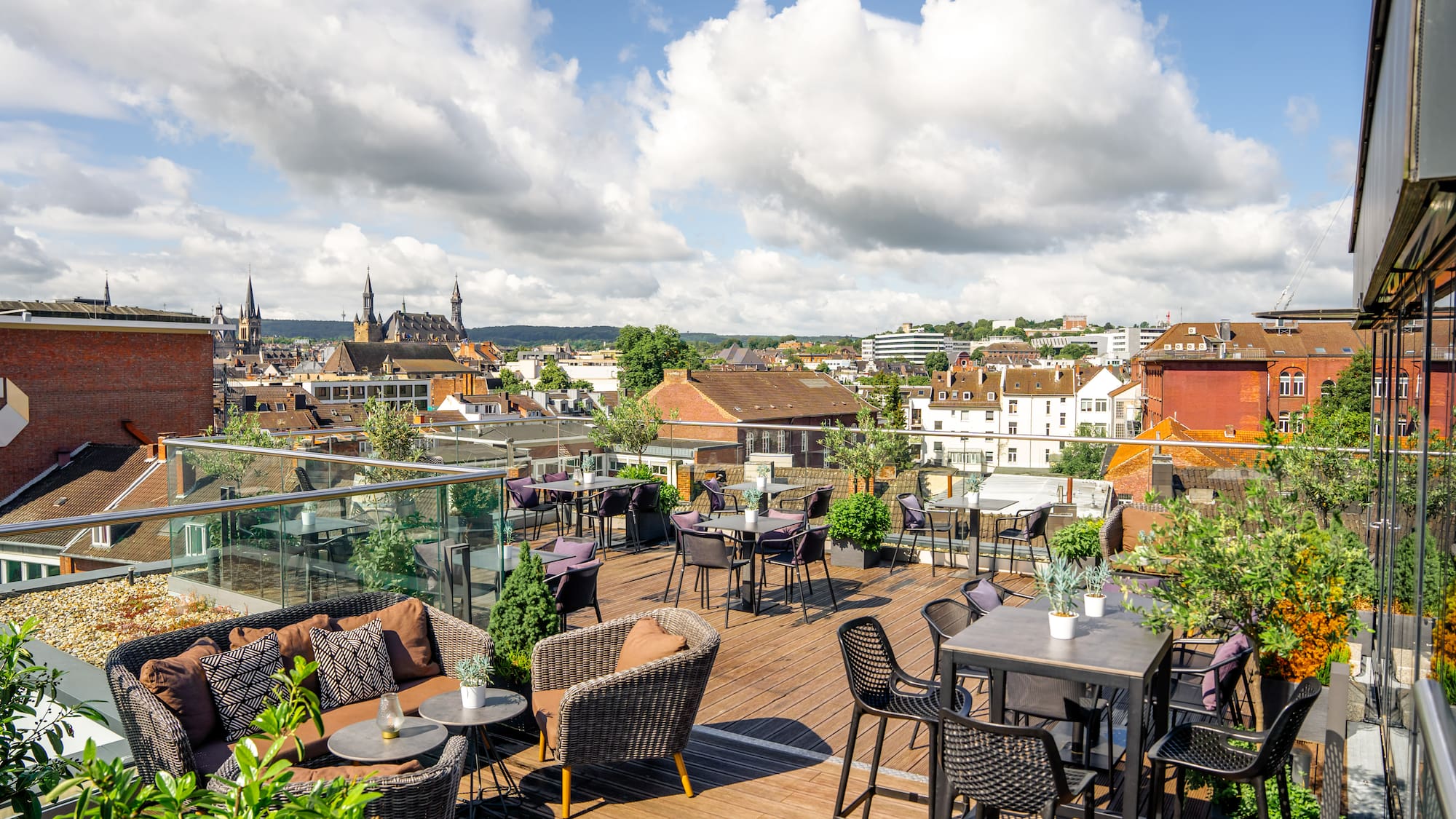 a rooftop patio with chairs and tables and a city in the background