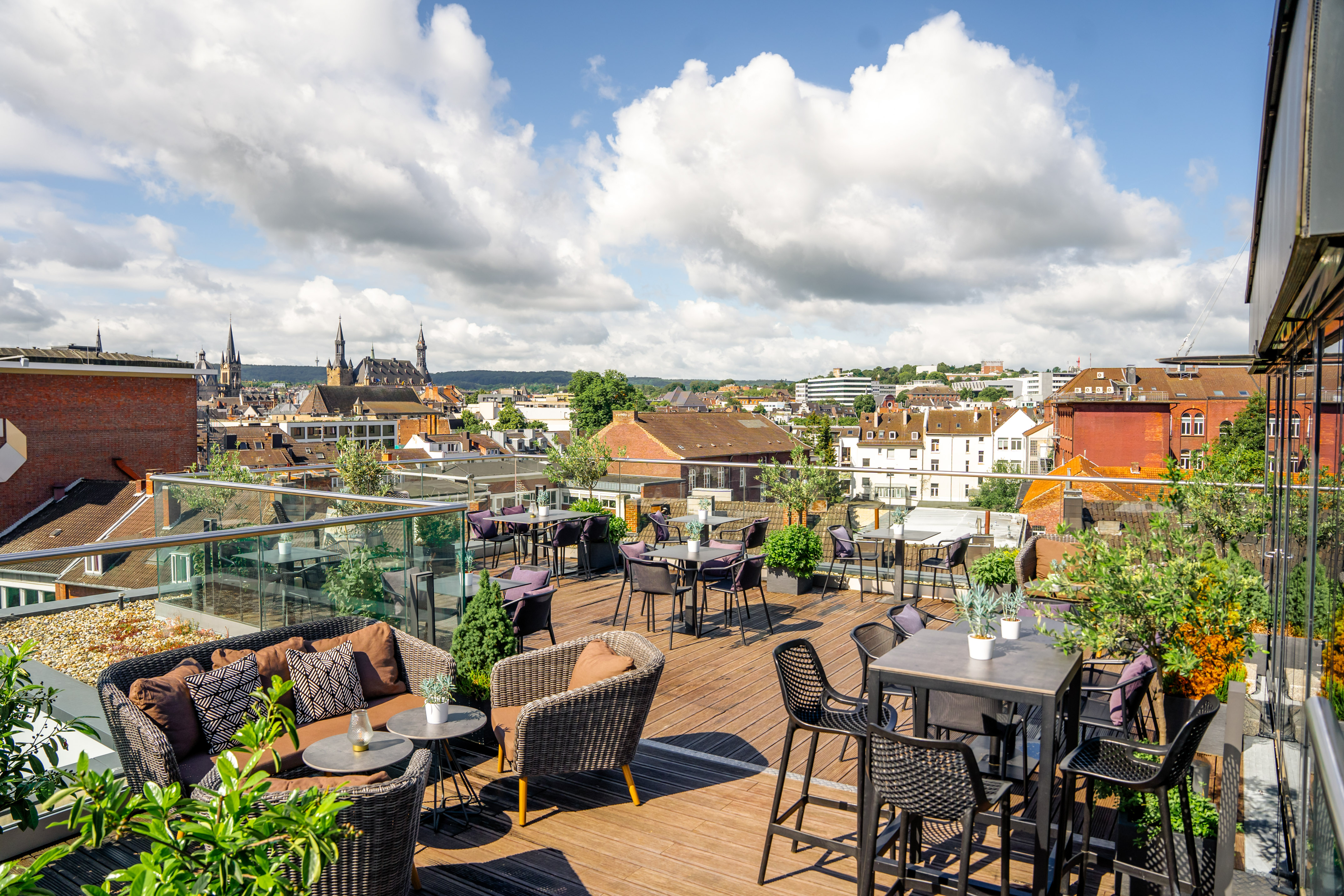 a rooftop patio with chairs and tables and a city in the background