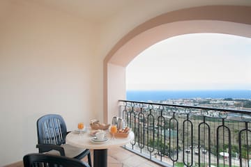 a table with food on it and chairs on a balcony overlooking the ocean