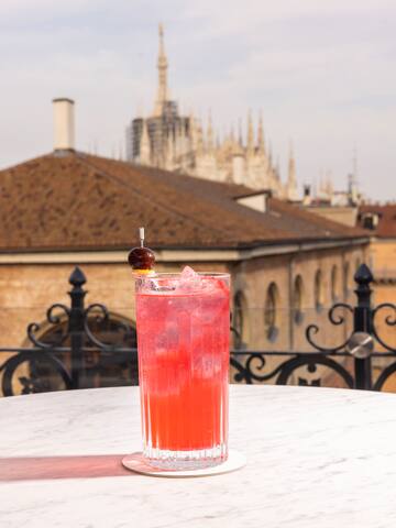 a glass of red liquid with a cherry on top of it