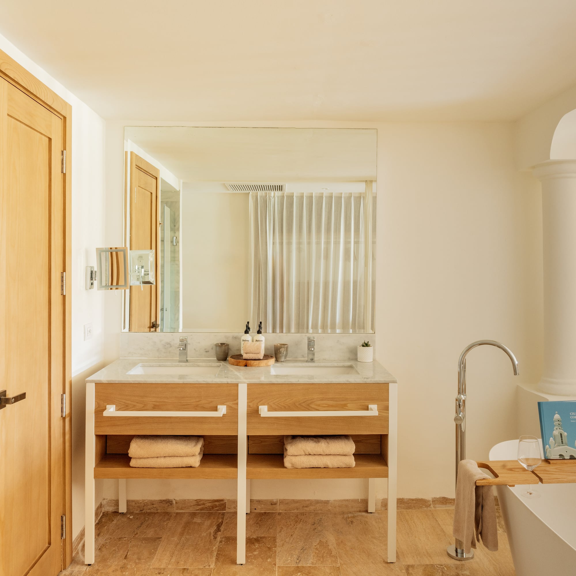 Modern bathroom: double marble vanity, wooden base, freestanding tub, shower.