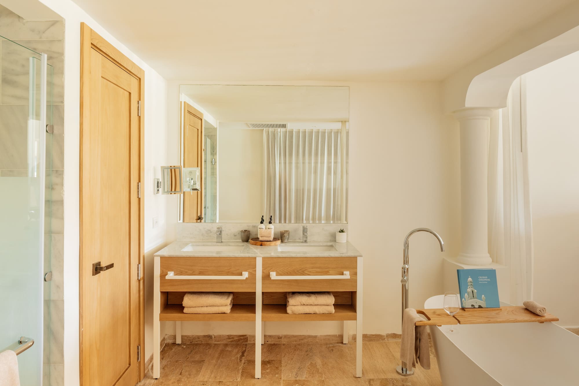 Modern bathroom: double marble vanity, wooden base, freestanding tub, shower.