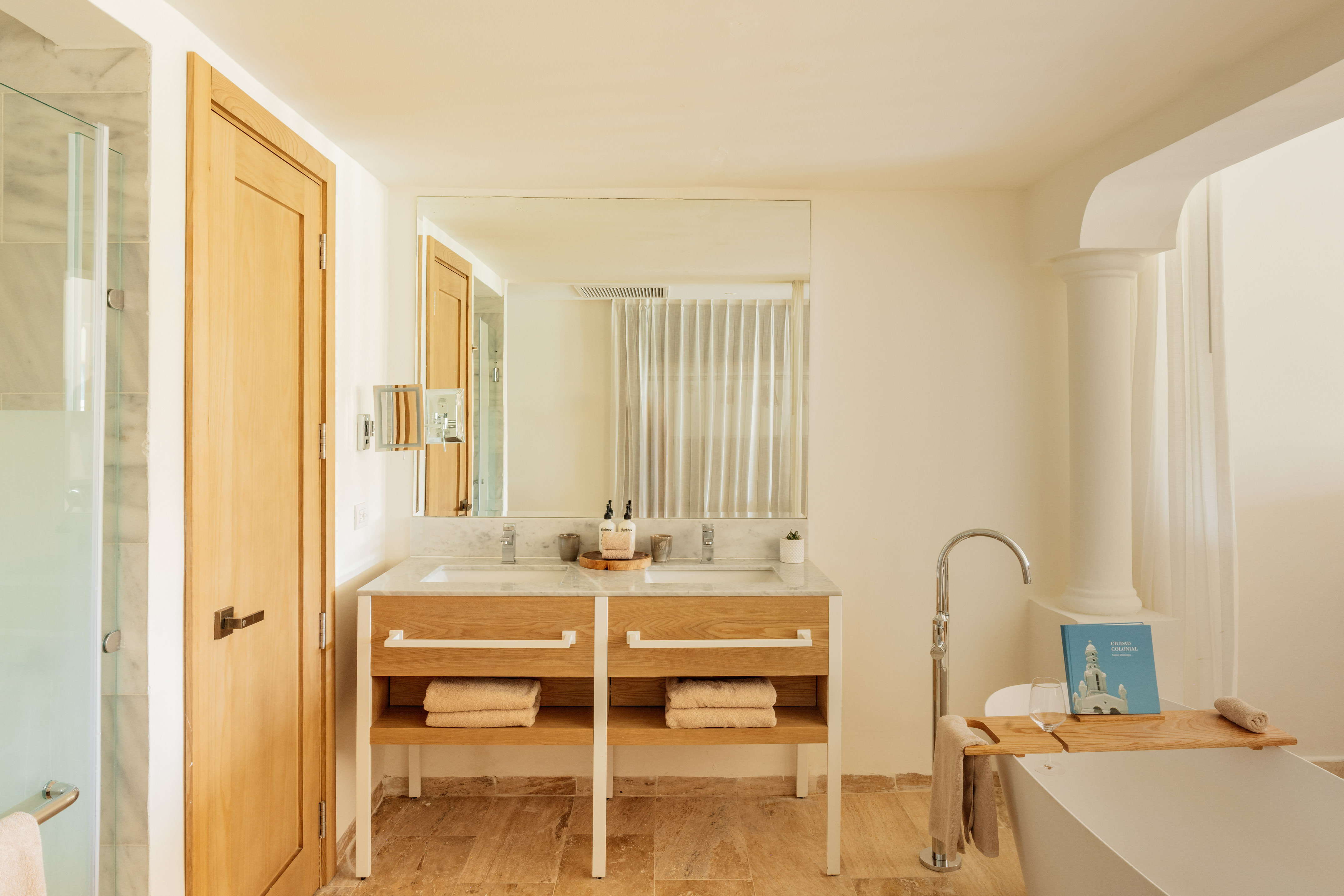 Modern bathroom: double marble vanity, wooden base, freestanding tub, shower.