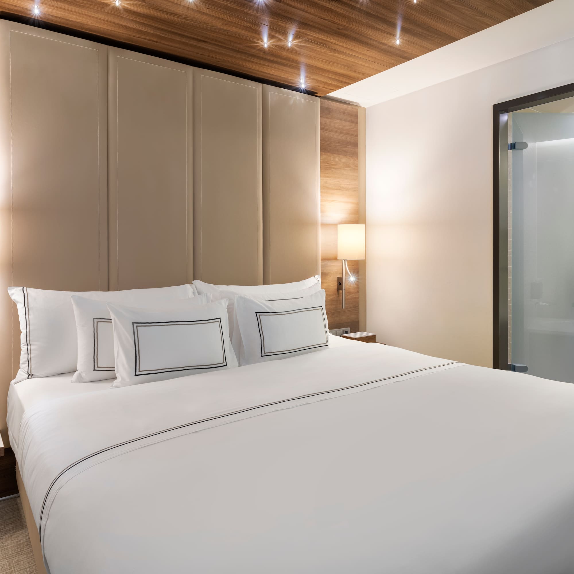 a bed with white sheets and a wood paneled headboard