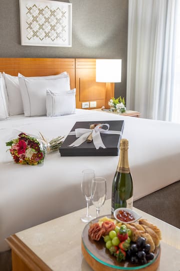 a gift box on a bed with a bottle of champagne and flowers