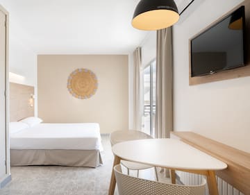 a room with a bed and a table and a television